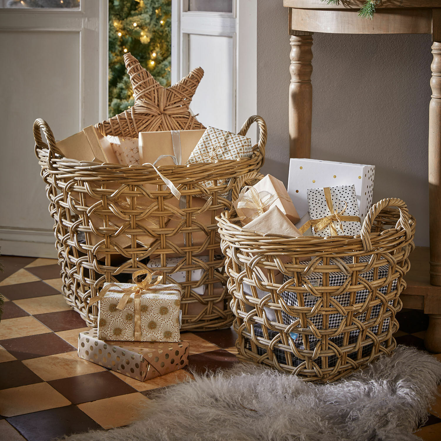 Mand set van 2 Qivoran Twee natuurlijke rieten manden met cadeaus en kerstdecoraties op een betegelde vloer.