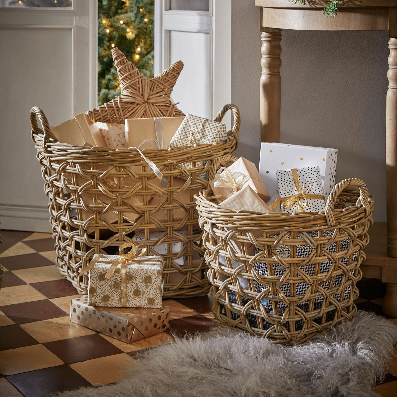 Lot de 2 corbeilles Qivoran Deux paniers en osier naturel remplis de cadeaux et décorations de Noël sur un sol carrelé.