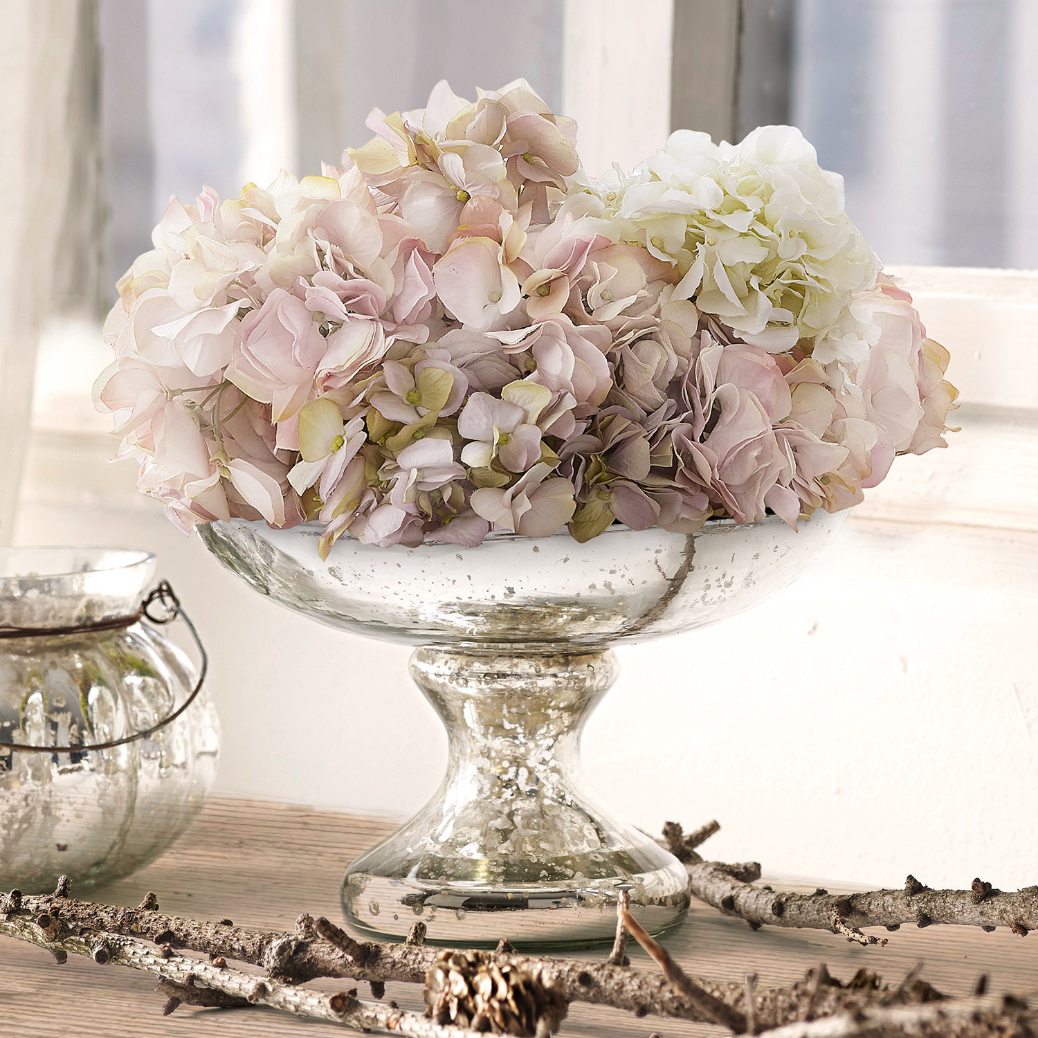 Schaal Estelle Glazen schaal op voet met pastelkleurige hortensia bloemen op lichte houten tafel