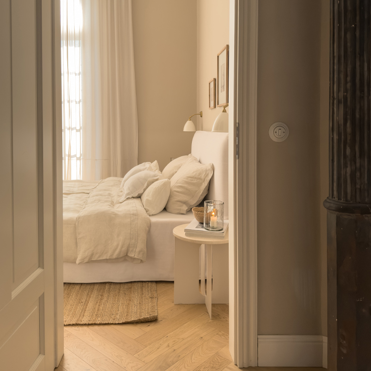 Chambre chaleureuse avec lit blanc, linge de lit beige et parquet en bois clair style scandinave