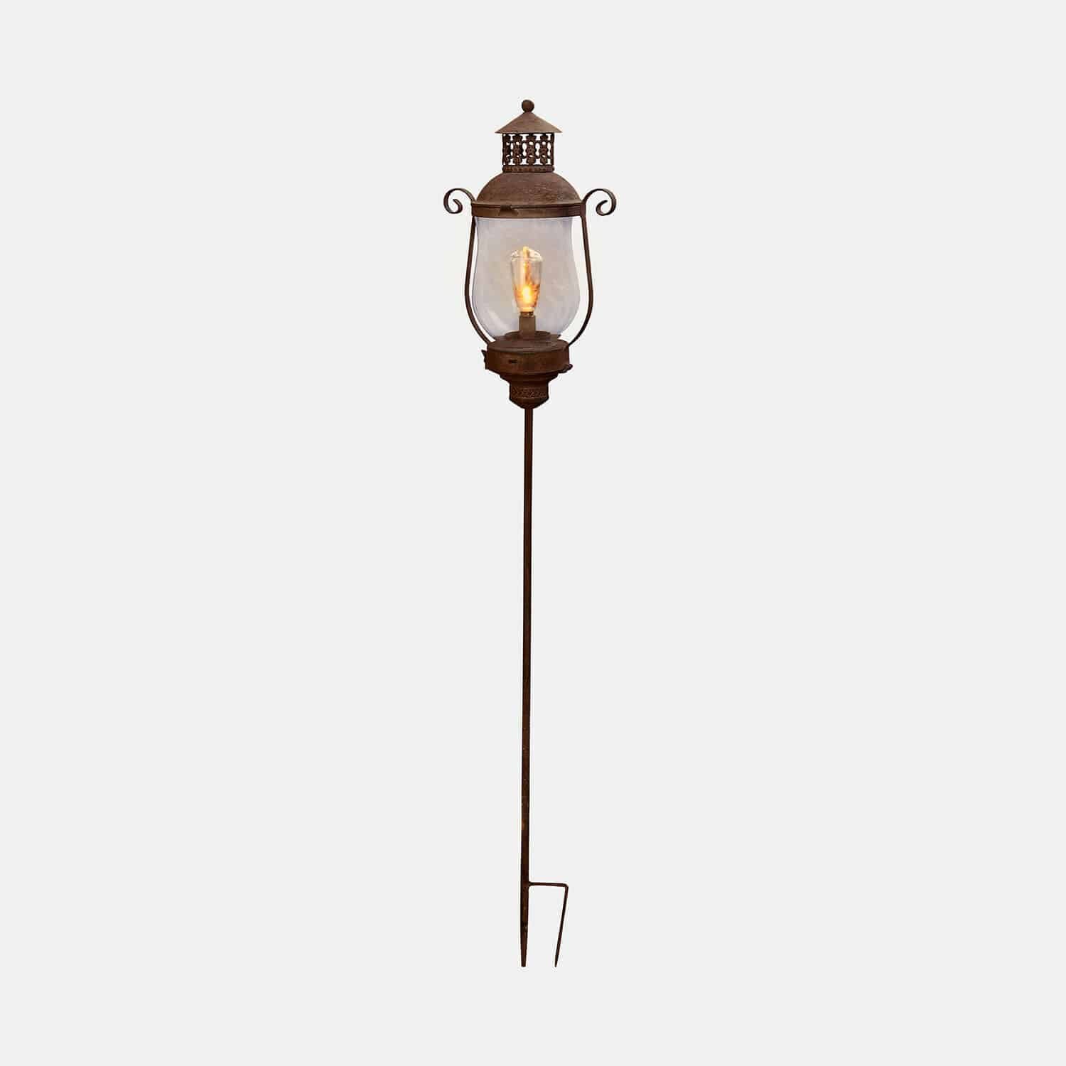 Decoratieve tuinlamp van roestig metaal met doorzichtige kap en warm licht