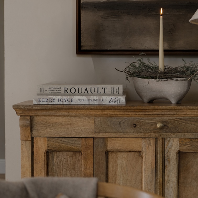 Buffet en bois avec deux livres et une bougie dans un bol en céramique sur une table décorative