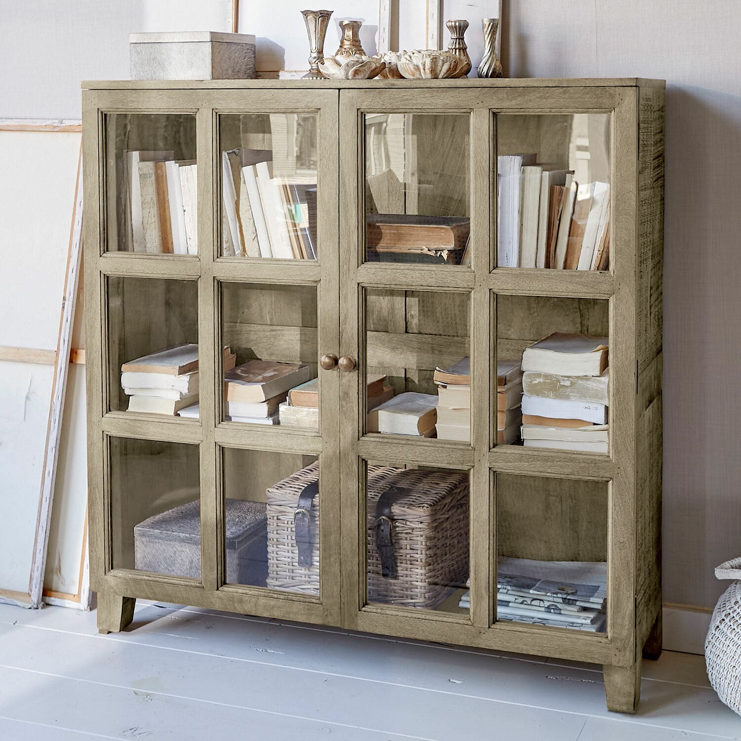 Kast Stoneham Beige houten kast met glazen deuren, gevuld met boeken en decoraties, stijlvolle woonkamermeubel