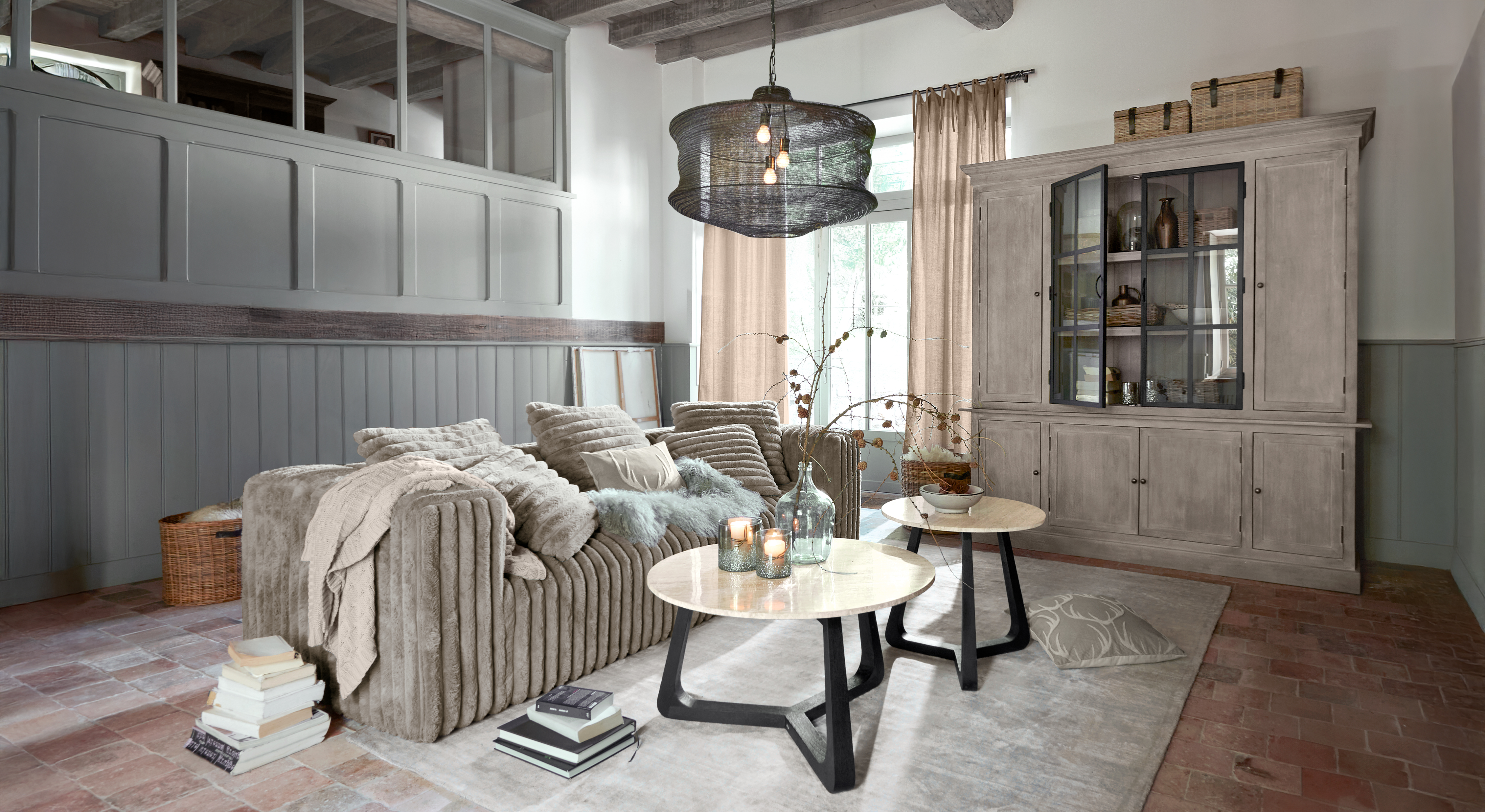Salon chaleureux avec canapé beige en tissu doux et deux tables basses rondes avec plateaux en marbre