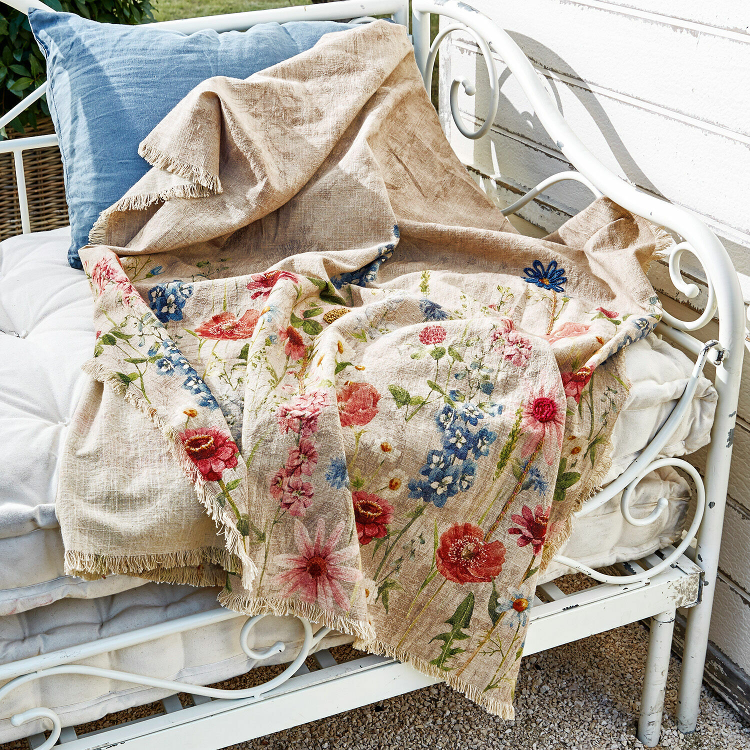 Plaid Eleonoire Plaid en lin beige avec motif floral coloré et franges sur banc en métal blanc