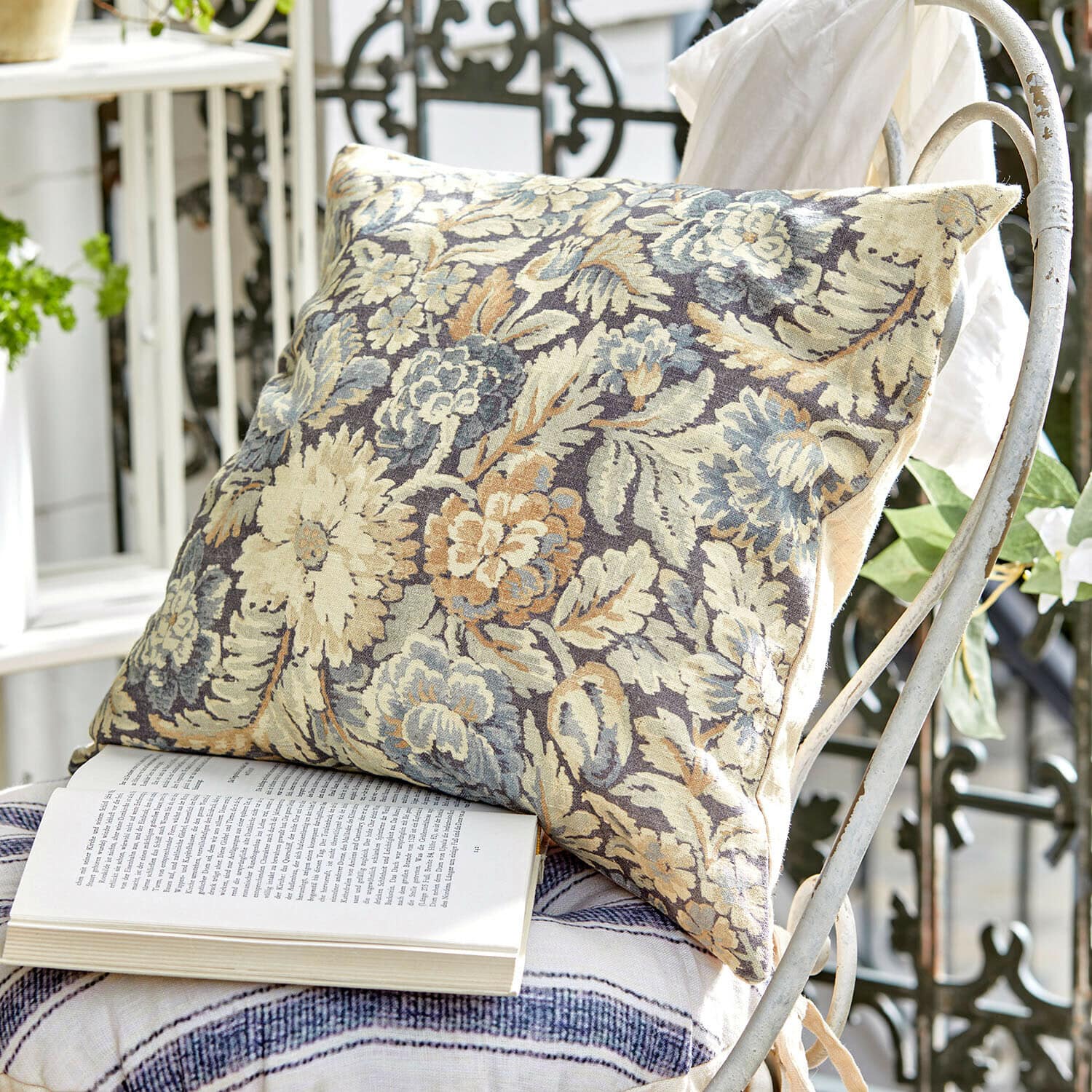 Kussenhoes Lumielle Decoratief kussen van stof met bloemenpatroon in beige en blauw op een witte metalen stoel