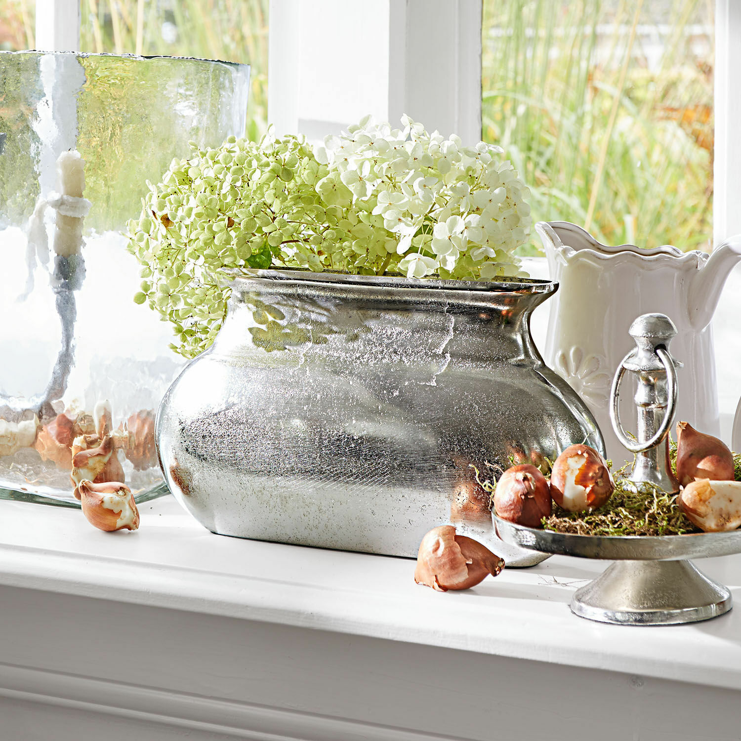 Vaas Melisique Zilveren metalen vaas met groen-witte hortensia op vensterbank met decoratieve bollen