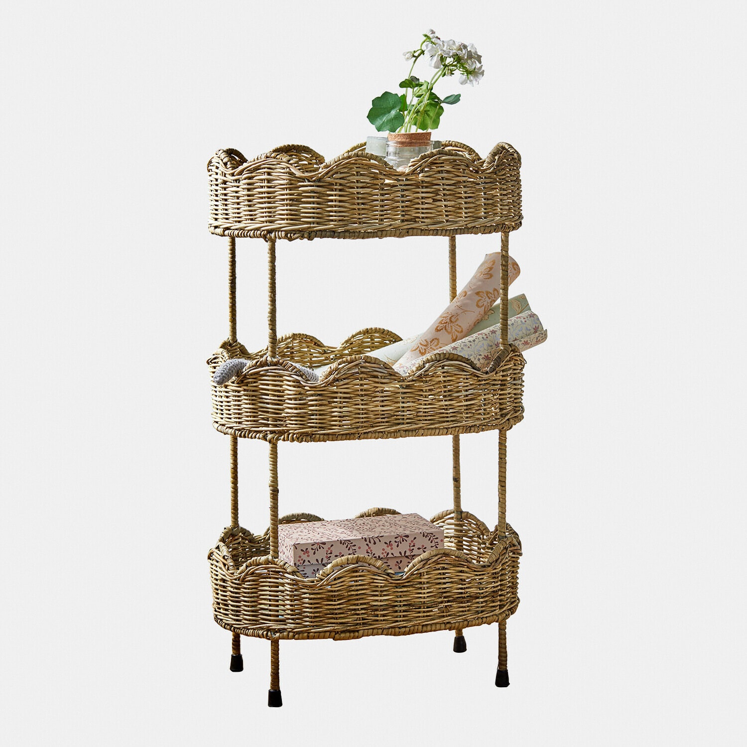 Étagère à trois niveaux en osier naturel avec objets décoratifs et plante verte