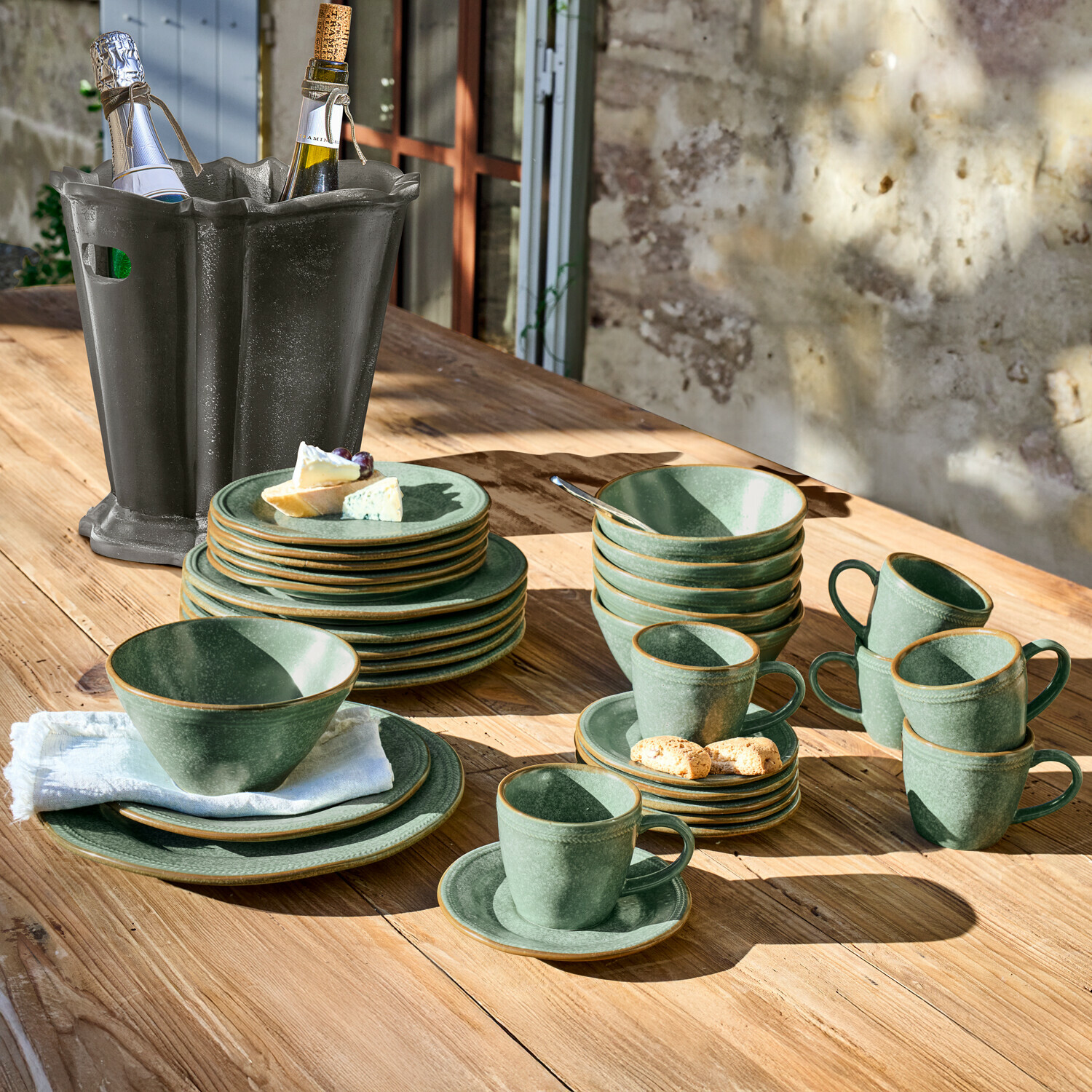 Servies set van 30 Norrvik Set groene steengoed servies op houten tafel met zwarte wijnkoeler ernaast