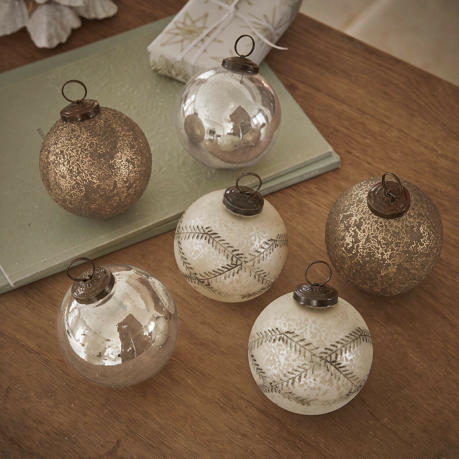 Ensemble de six boules de Noël en verre doré avec différentes textures posées sur une table en bois