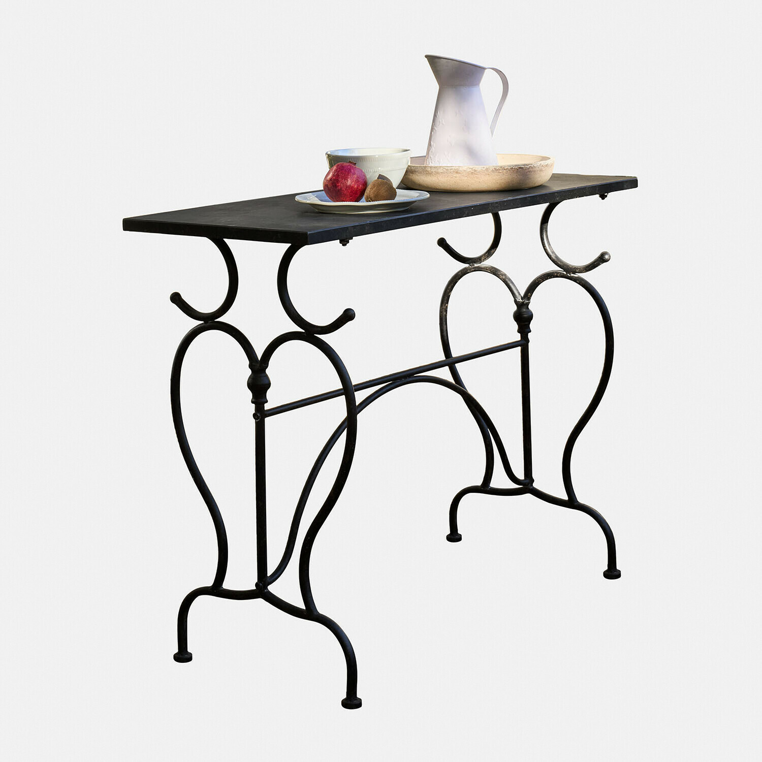 Table en métal noir avec pieds décoratifs et plateau, décorée de vaisselle et fruits