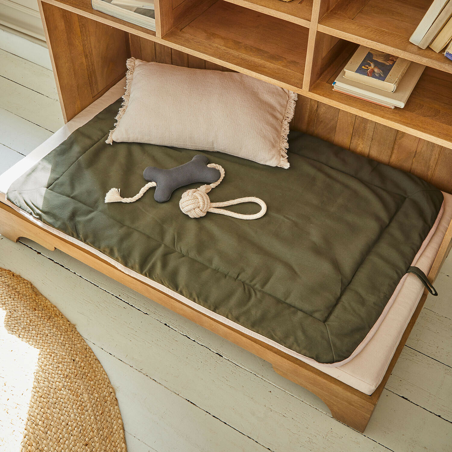 Huisdierenmat Dunelyn Groene mat en beige kussen van stof op houten hondenbed met kauwspeelgoed