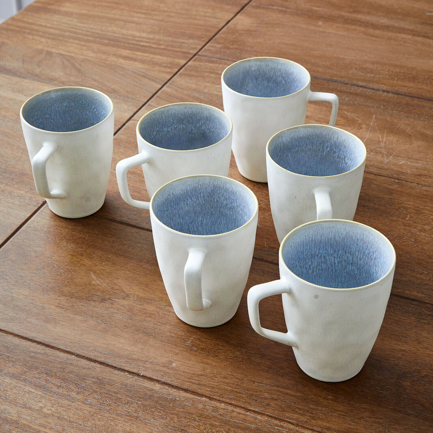 Kopje set van 6 Vionette Set van zes crèmekleurige keramische mokken met blauwe binnenkant op houten tafel