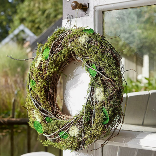 Natuurlijke krans van mos en takken met groene bladeren, buitendeurdecoratie
