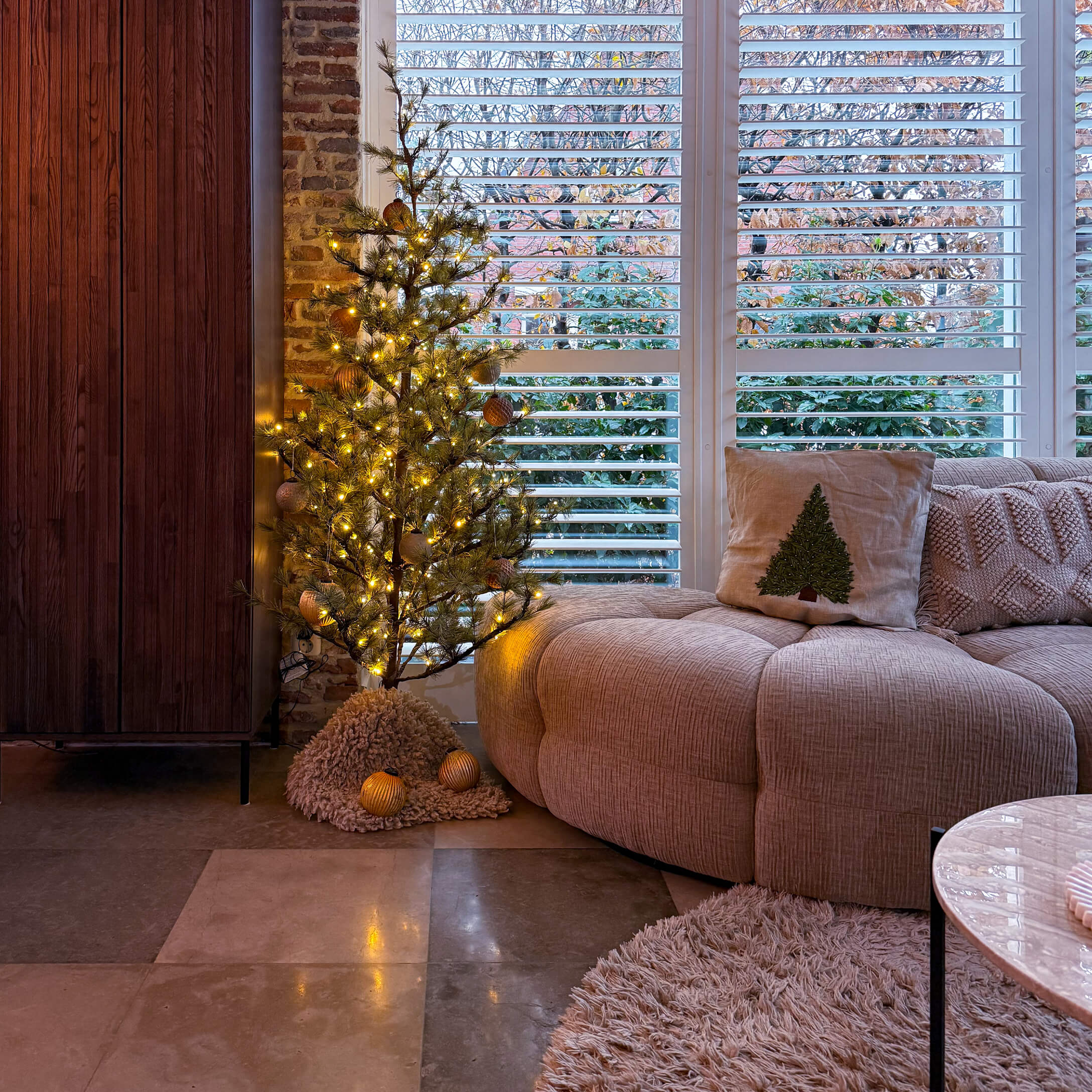 Salon chaleureux avec canapé beige, coussin sapin et petit sapin décoratif lumineux LED