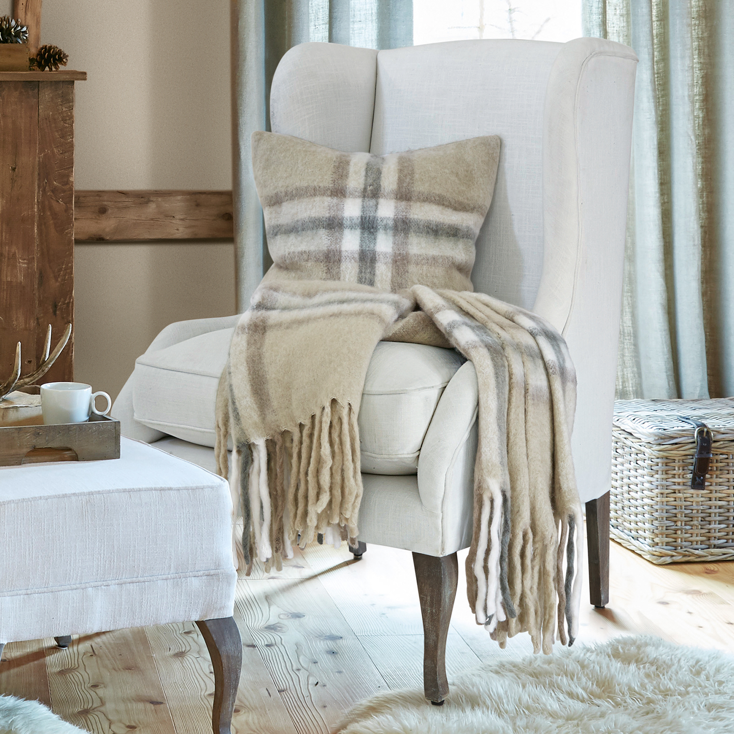 Beige wollen plaid en kussen met ruitpatroon op crèmekleurige stoel in gezellige woonkamer