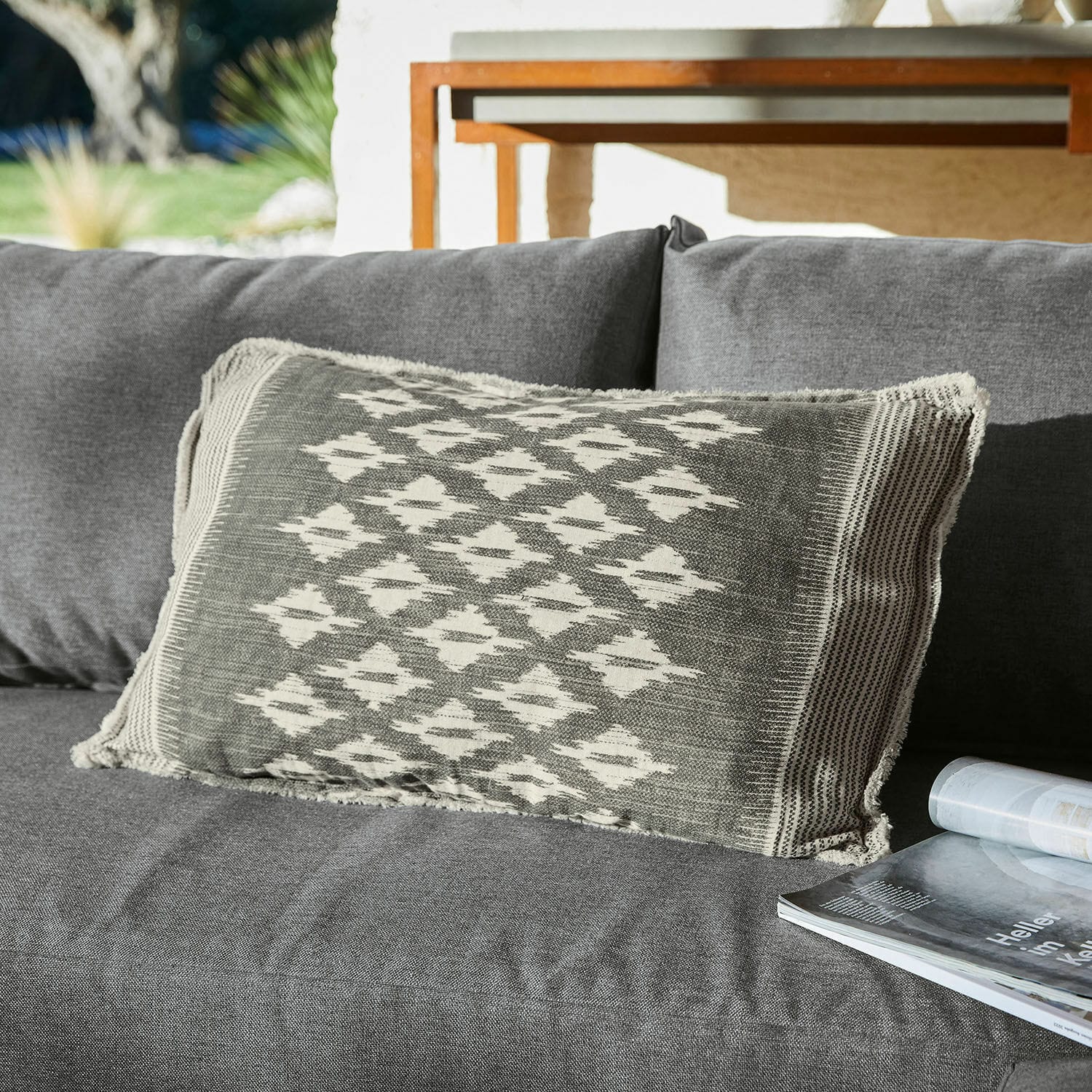 Coussin décoratif gris avec motif géométrique sur canapé gris, textile d'intérieur moderne