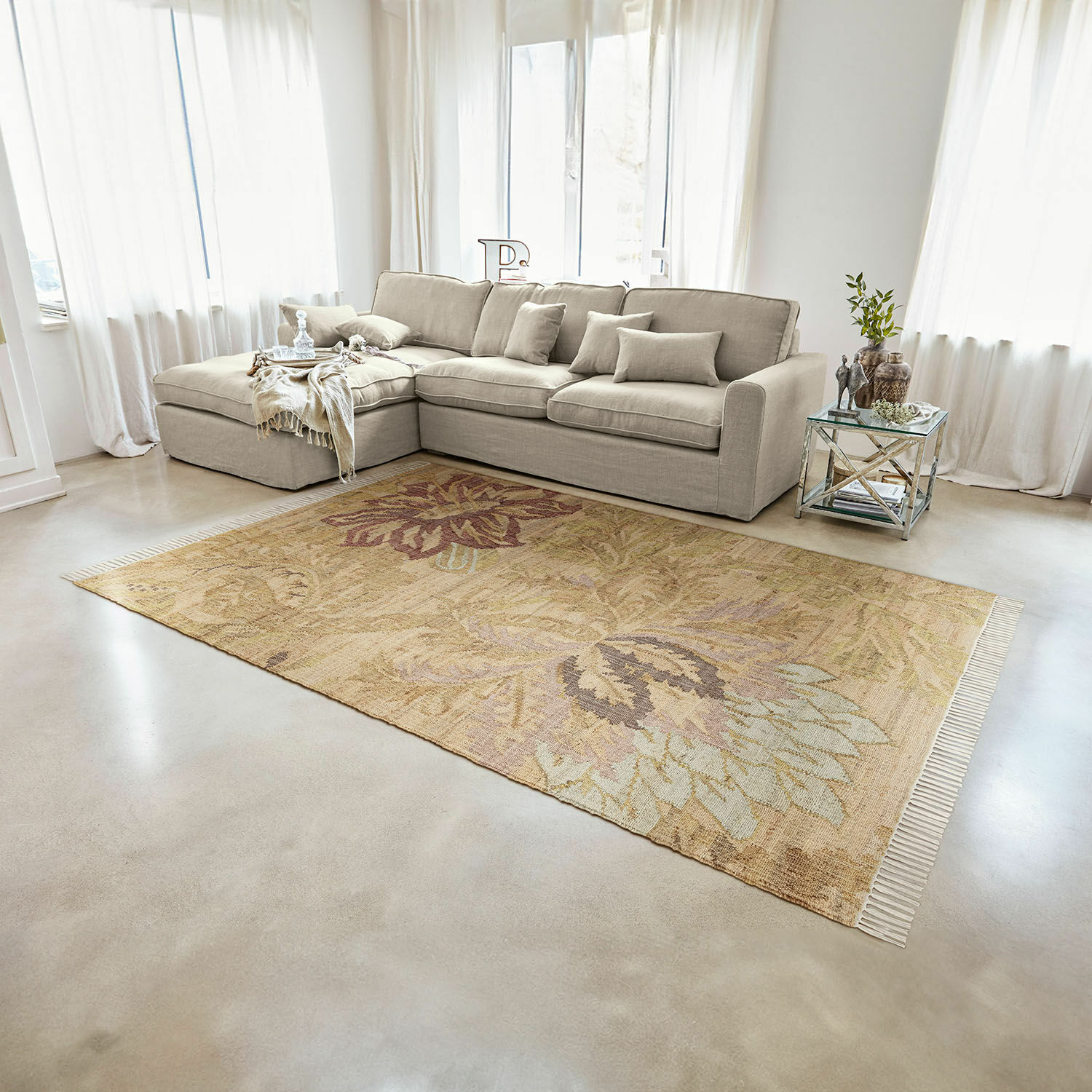Vloerkleed Willeque Beige vloerkleed met bloemmotief van natuurlijk materiaal in lichte woonkamer met grijze bank
