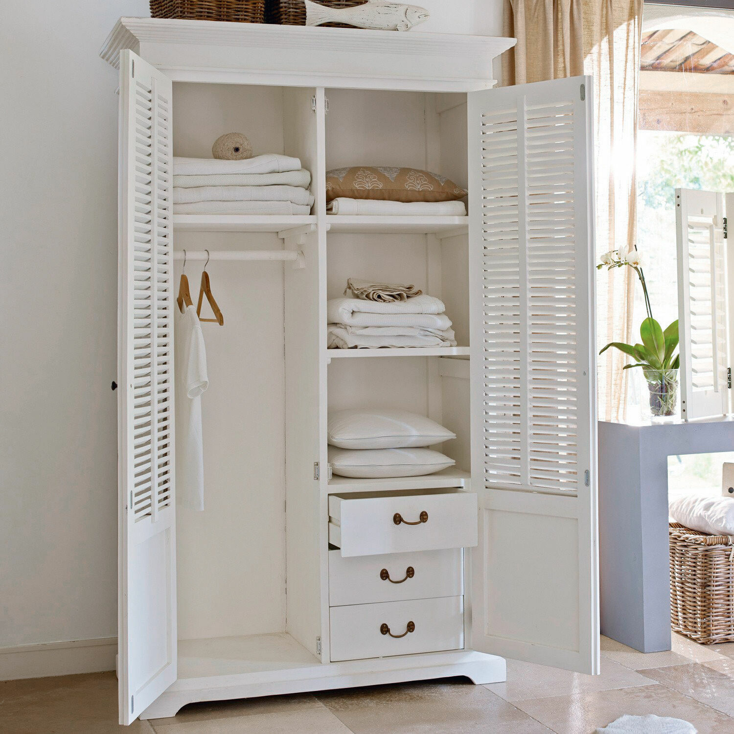 Armoire Williston Armoire en bois blanc avec portes à persiennes et étagères pour linge dans une pièce lumineuse