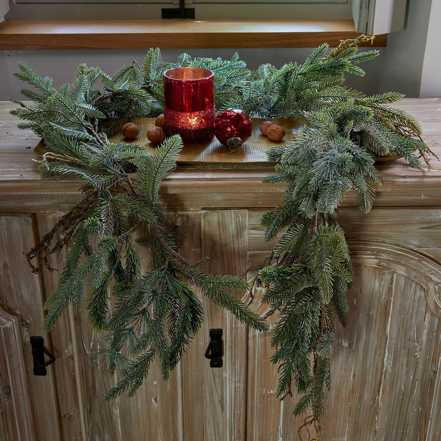 Guirlande Dolomera Decoratieve krans van groene dennentakken met rode kandelaar en noten op houten kast