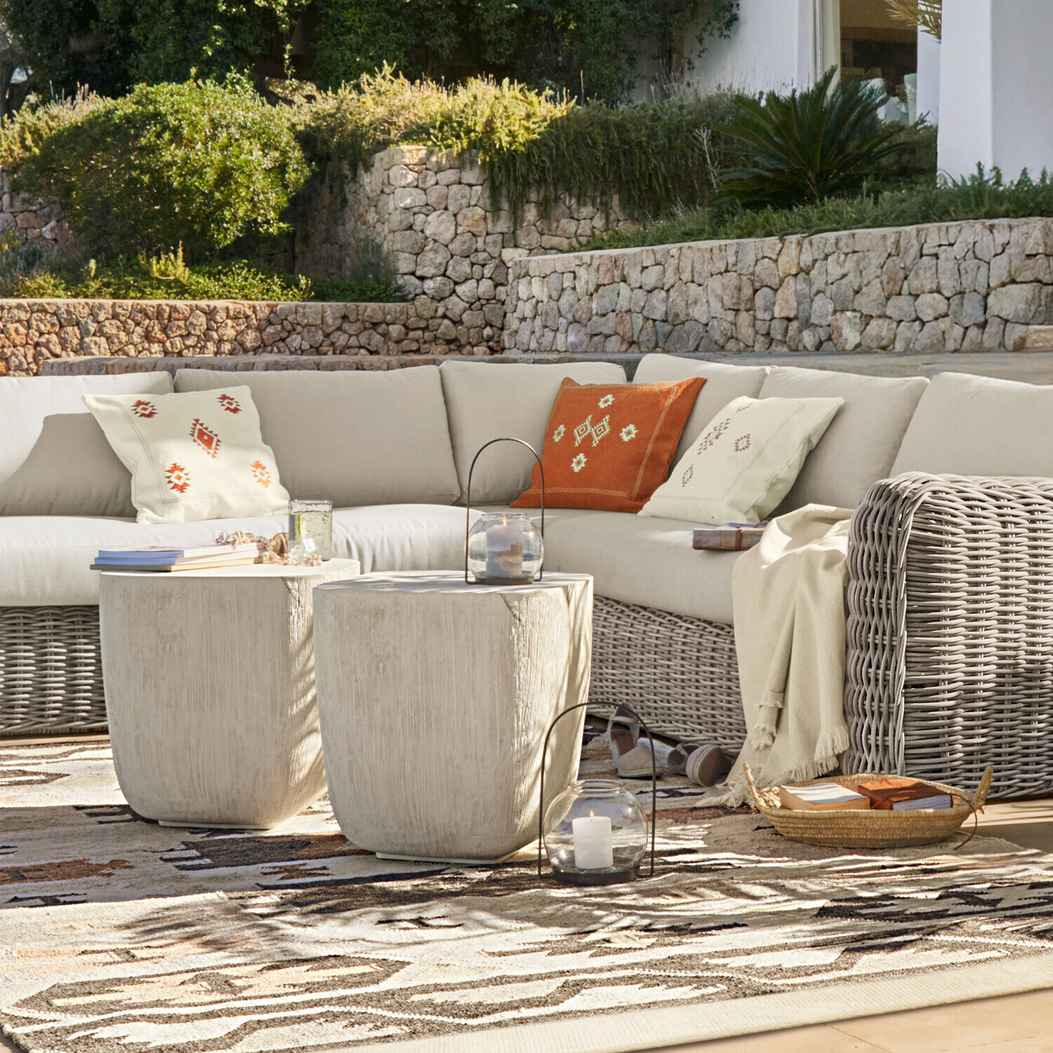 Fauteuil d’angle Eravinto Ensemble de mobilier d'extérieur avec canapé en rotin beige et deux tables basses claires sur terrasse