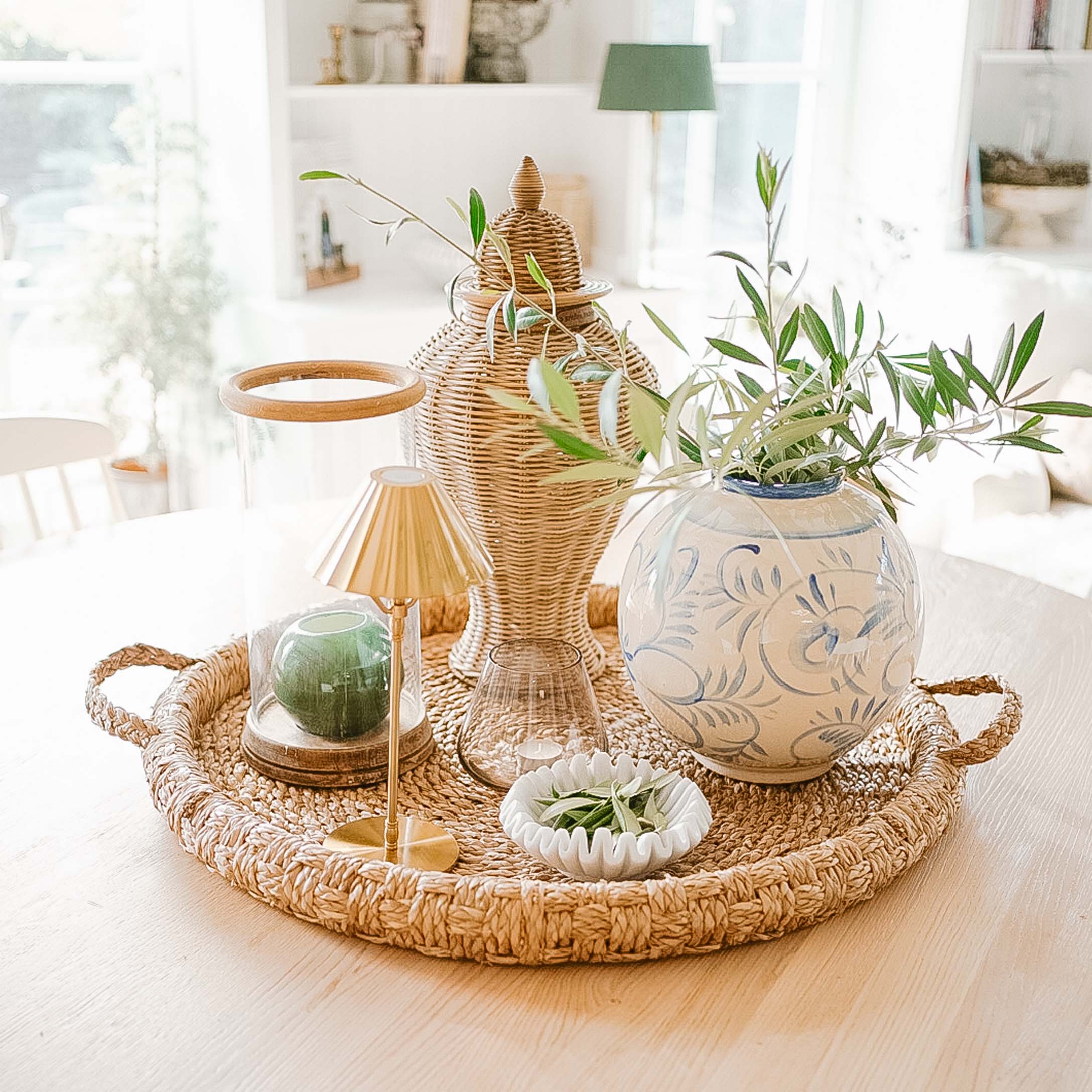 Plateau rond en osier avec vases décoratifs et bougies dans un intérieur lumineux et naturel