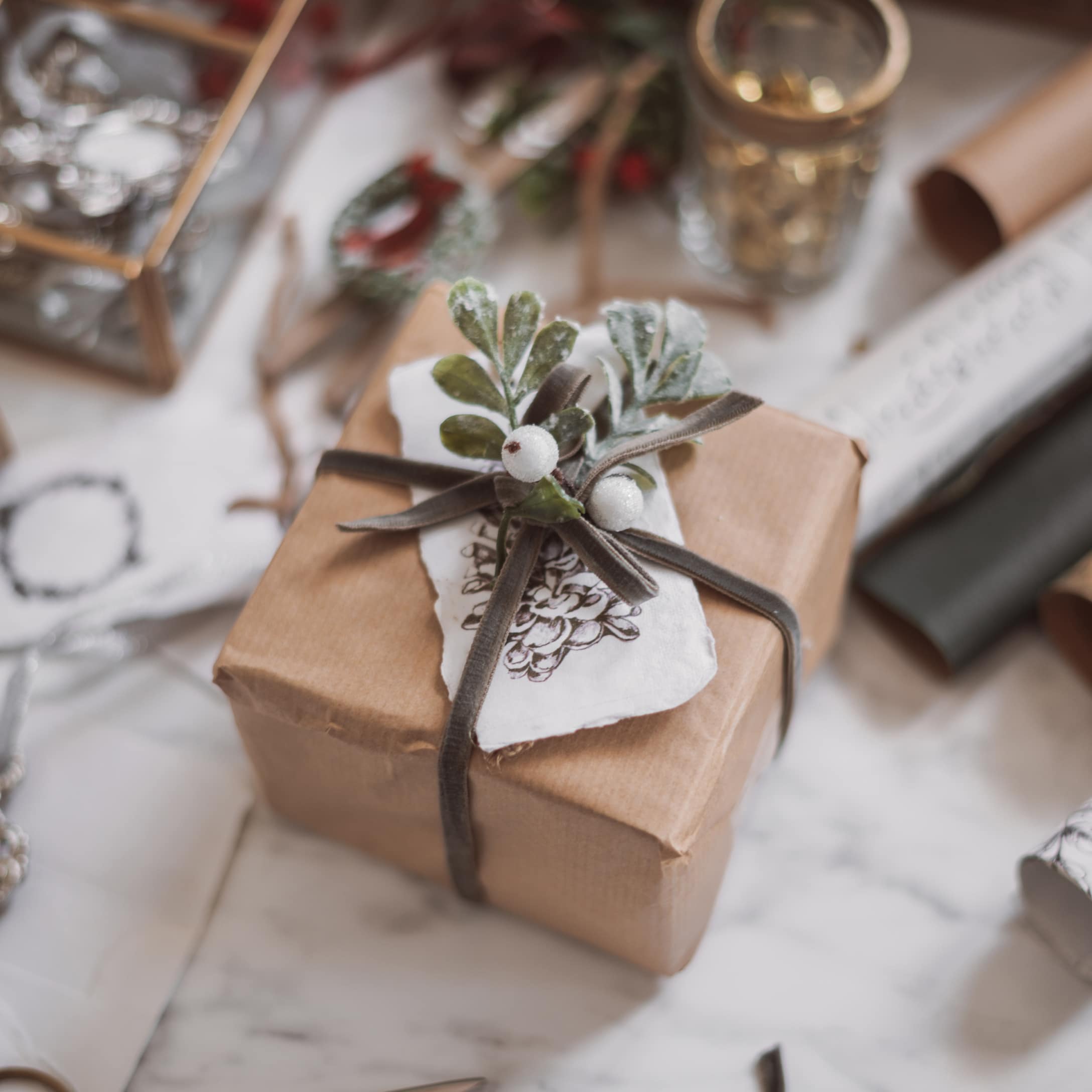 Cadeau verpakt in bruin papier met grijs lint en groene bladeren voor feestelijke sfeer