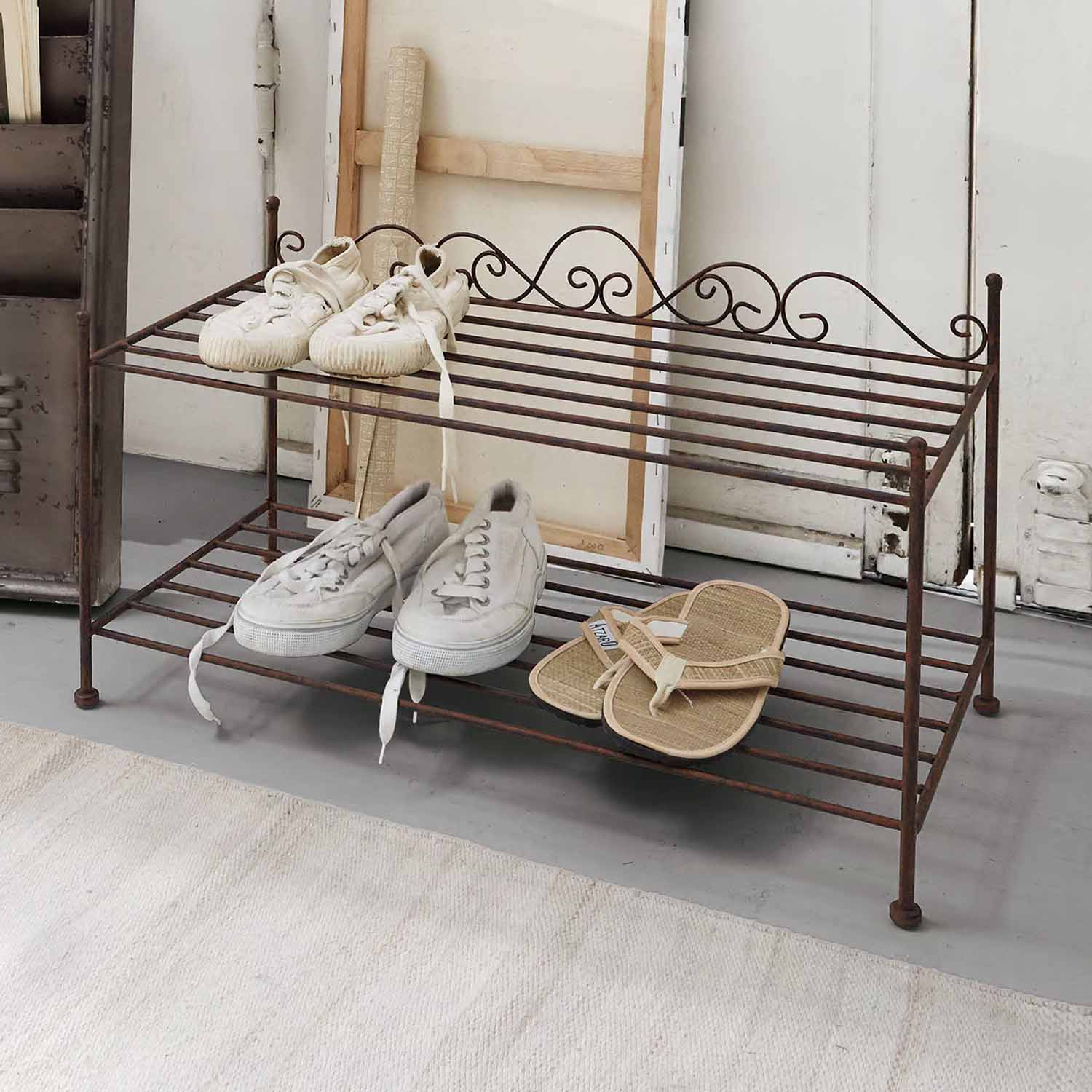 Twee verdiepingen metalen schoenenrek in vintage stijl met witte en beige schoenen met roestpatina