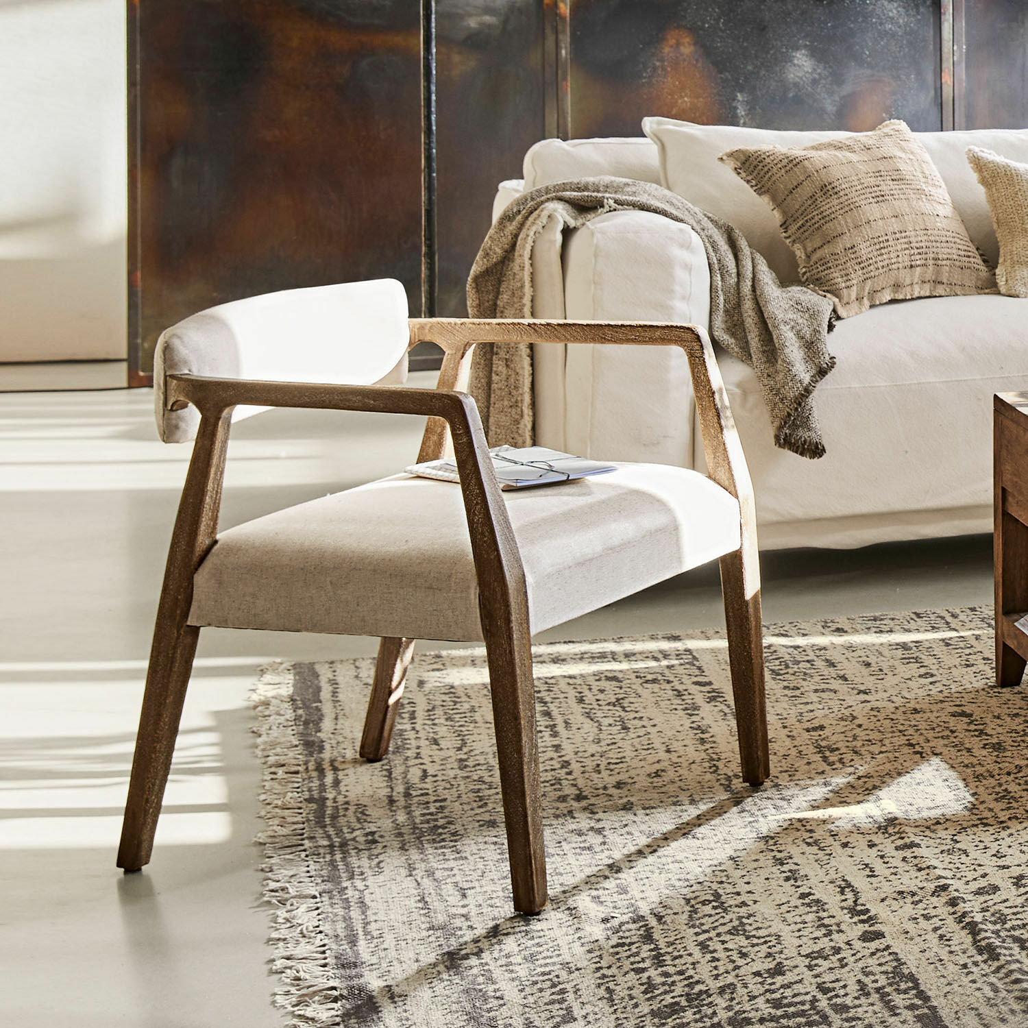 Fauteuil Bronwyn Moderne stoel met houten frame en lichte stofbekleding op tapijt in woonkamer