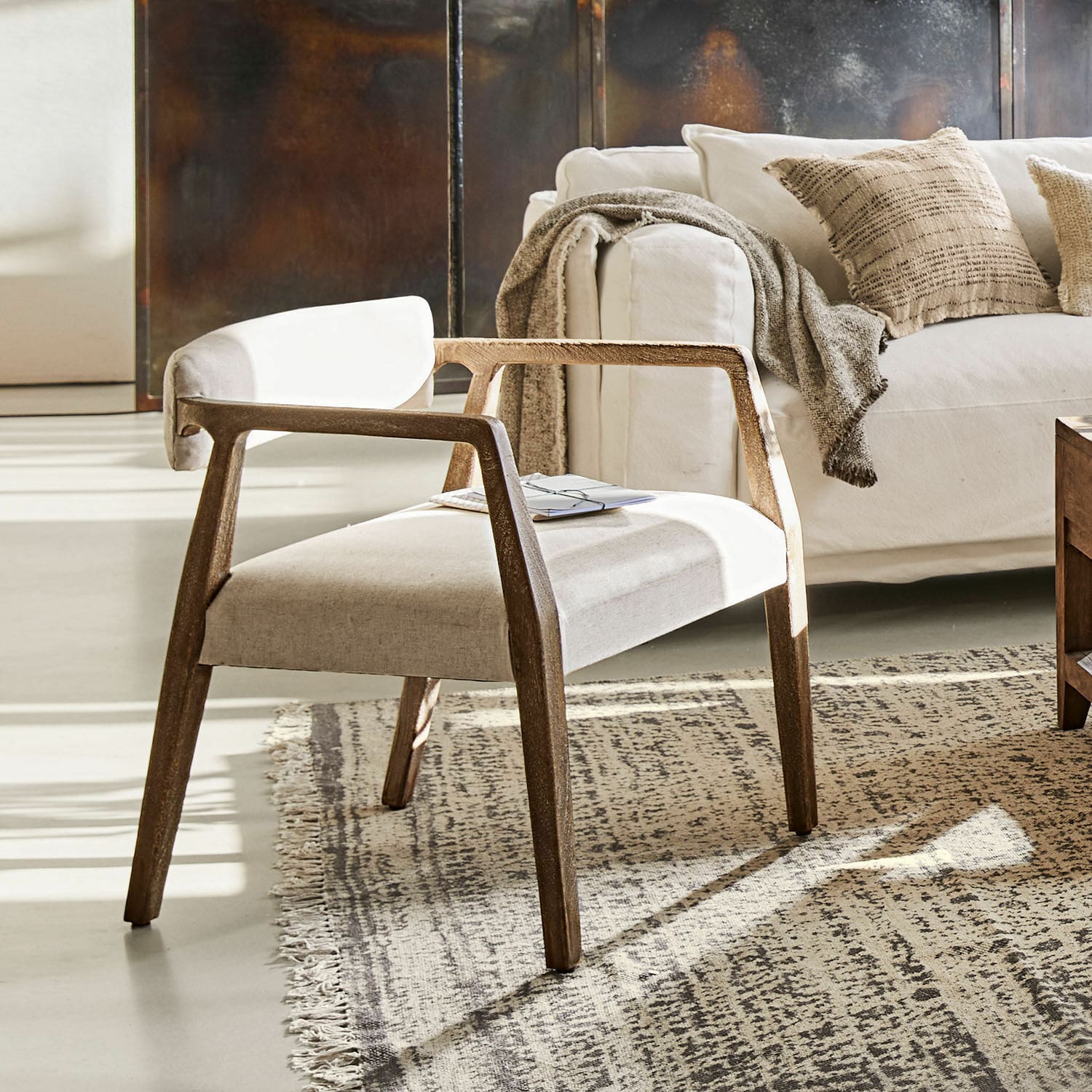 Fauteuil Bronwyn Moderne stoel met houten frame en lichte stofbekleding op tapijt in woonkamer