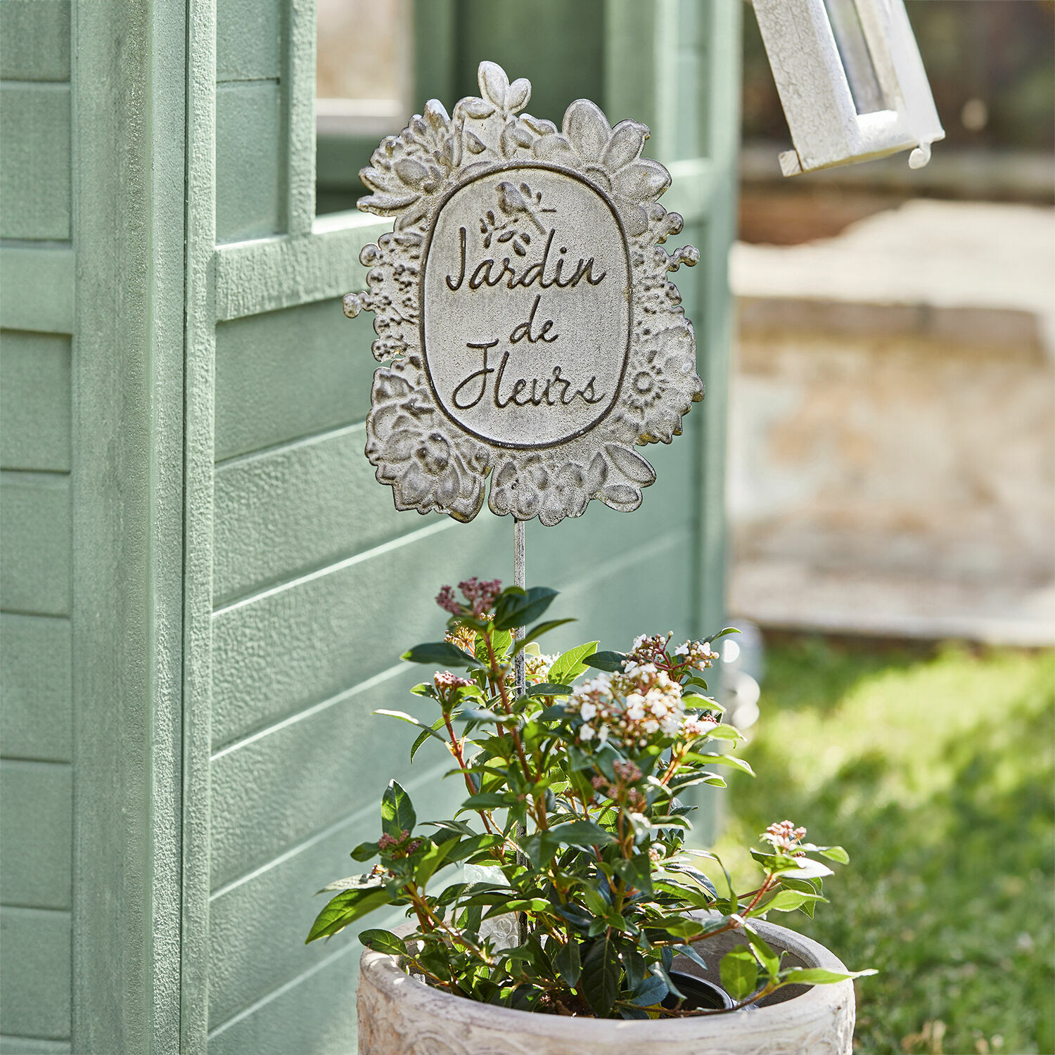 Metalen tuindecoratie met tekst Jardin de Fleurs in pot met groene bladeren en witte bloemen