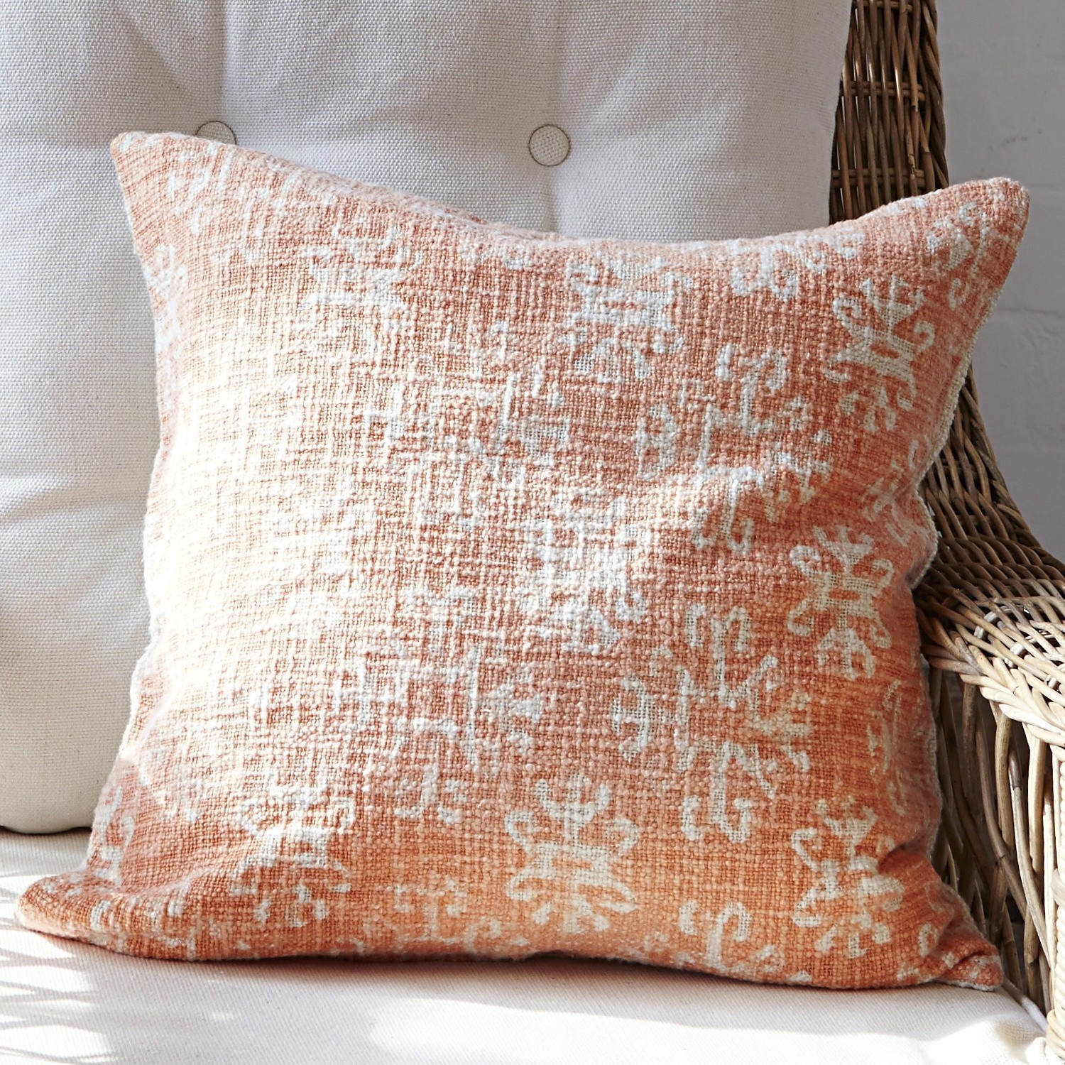 Coussin décoratif orange avec motif blanc en tissu texturé, idéal pour salon confortable