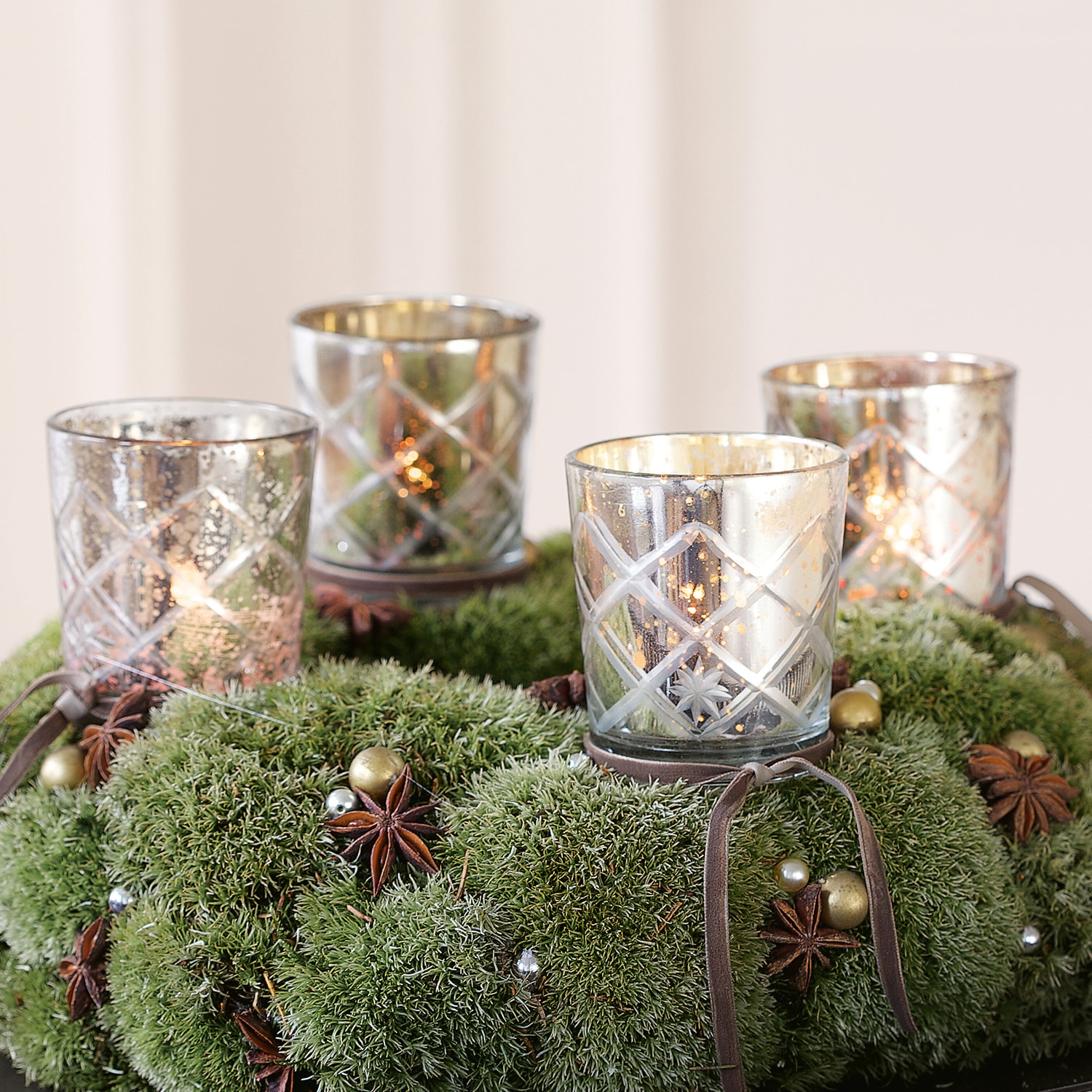 Photophores en verre à motif quadrillé sur une couronne de mousse verte décorée pour Noël