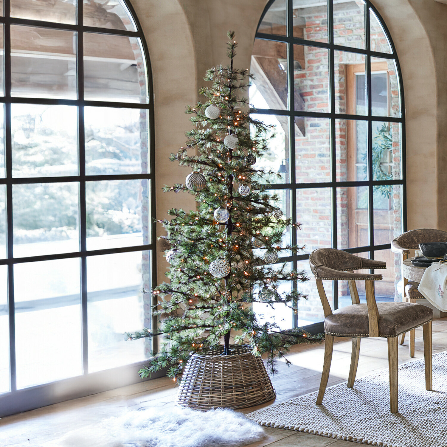 Sapin de Noël Sapi Sapin artificiel vert décoré de lumières LED dans un panier en osier dans un intérieur lumineux avec grandes fenêtres