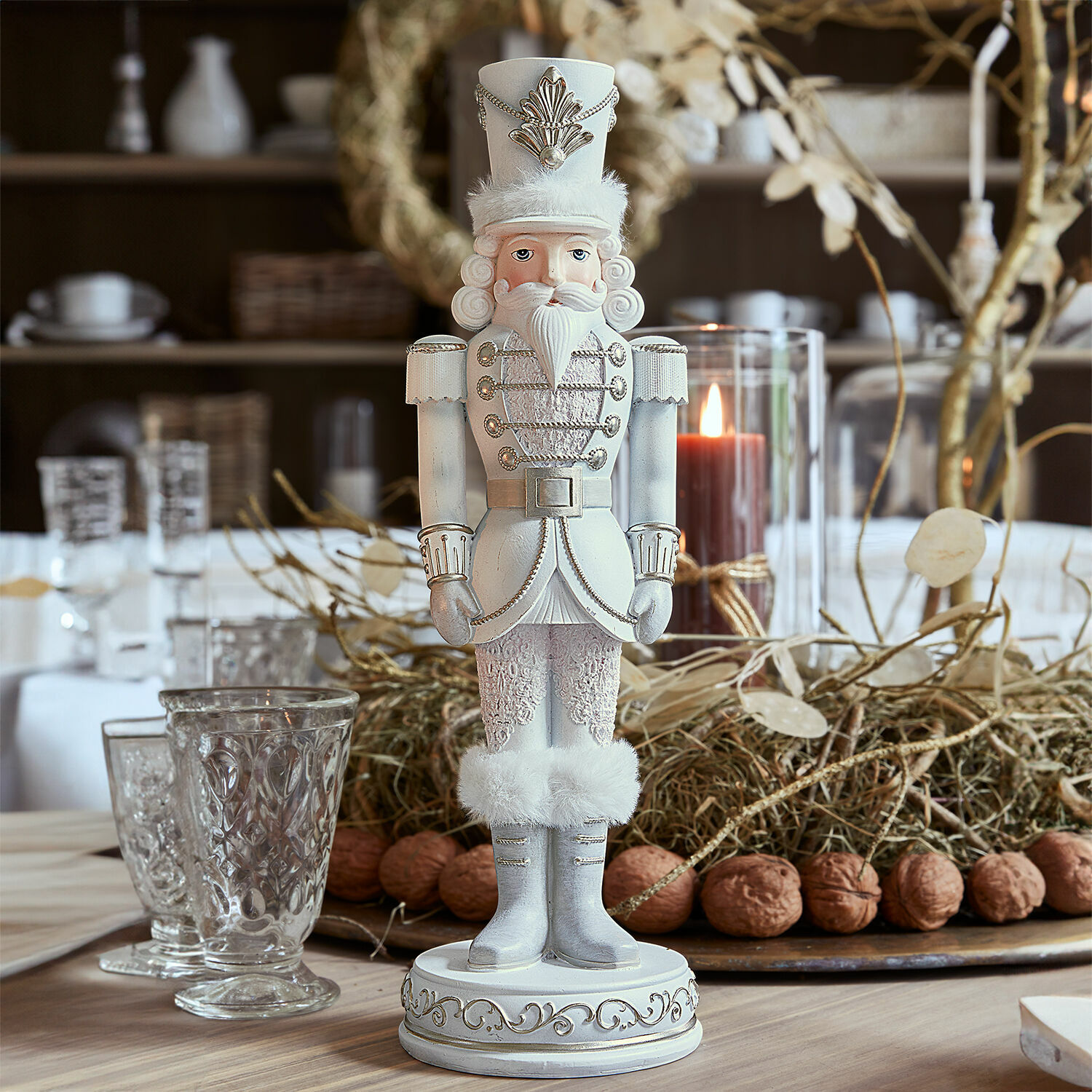 Casse-noix décoratif Moriette Casse-noisette en bois blanc avec détails en fourrure et ornements argentés sur une table de Noël
