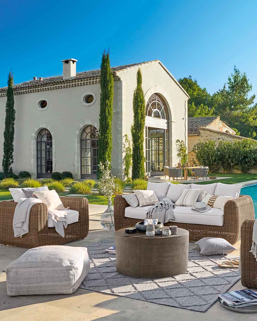 Ensemble de mobilier de jardin en rotin marron avec coussins blancs sur terrasse près de la piscine