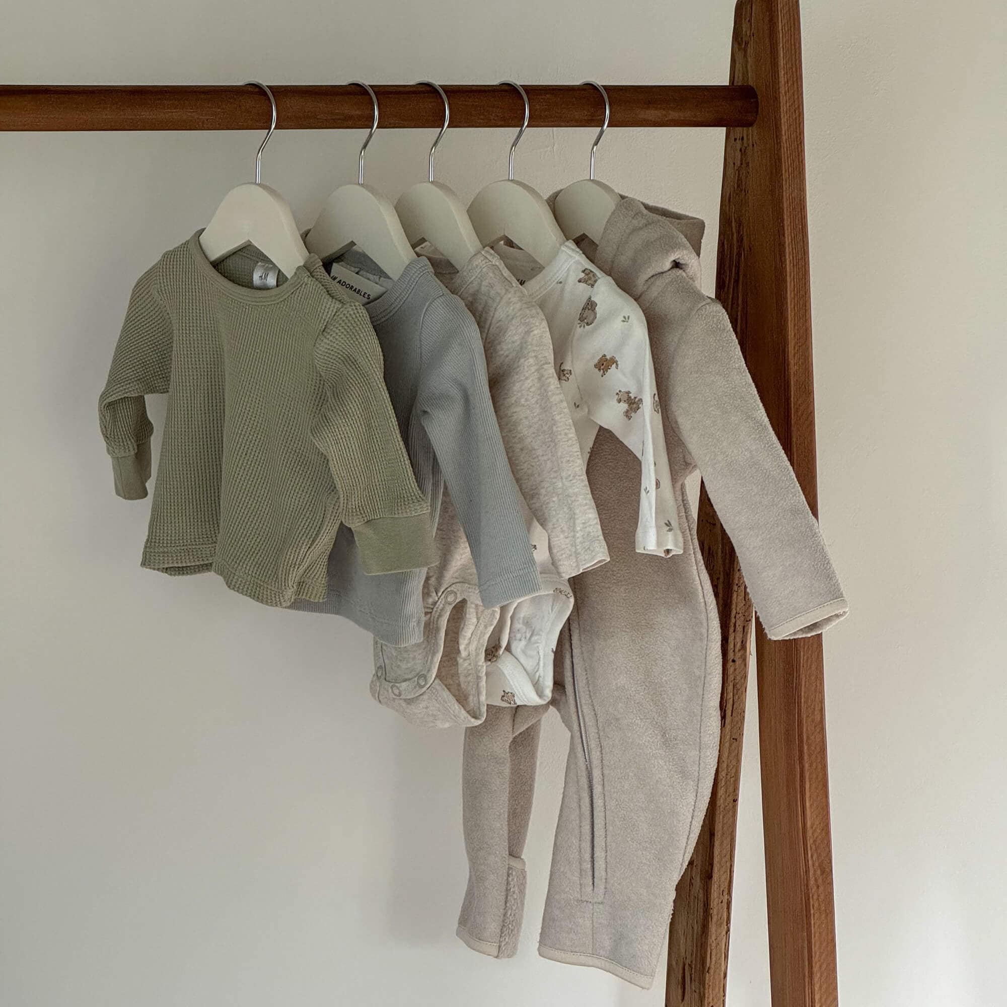 Set babykleding in neutrale kleuren aan hangers, zachte stoffen met berenmotief