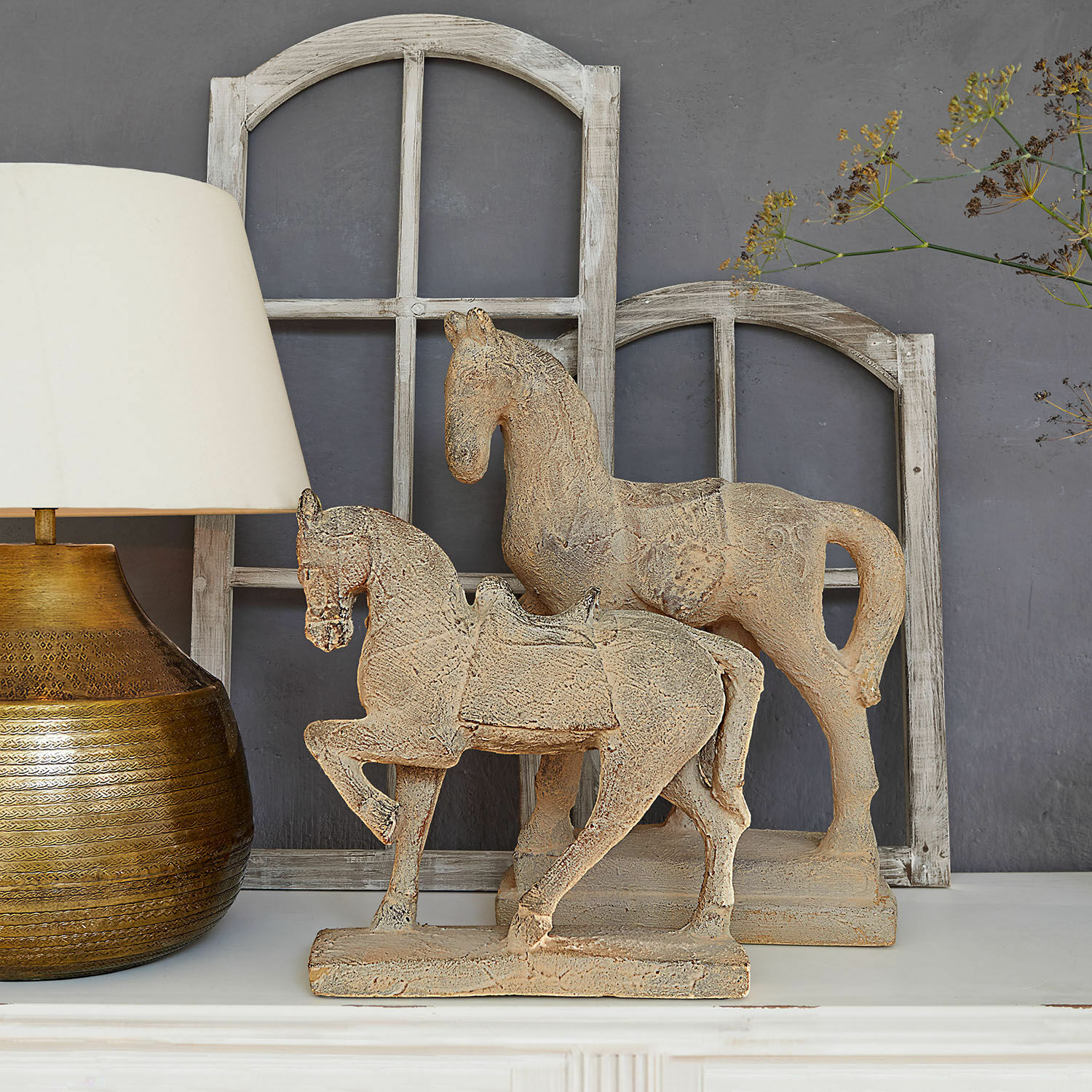 Lot de 2 chevaux décoratifs Mirandel Figurines décoratives de chevaux en pierre beige sur une étagère blanche avec lampe et cadres de fenêtres en bois