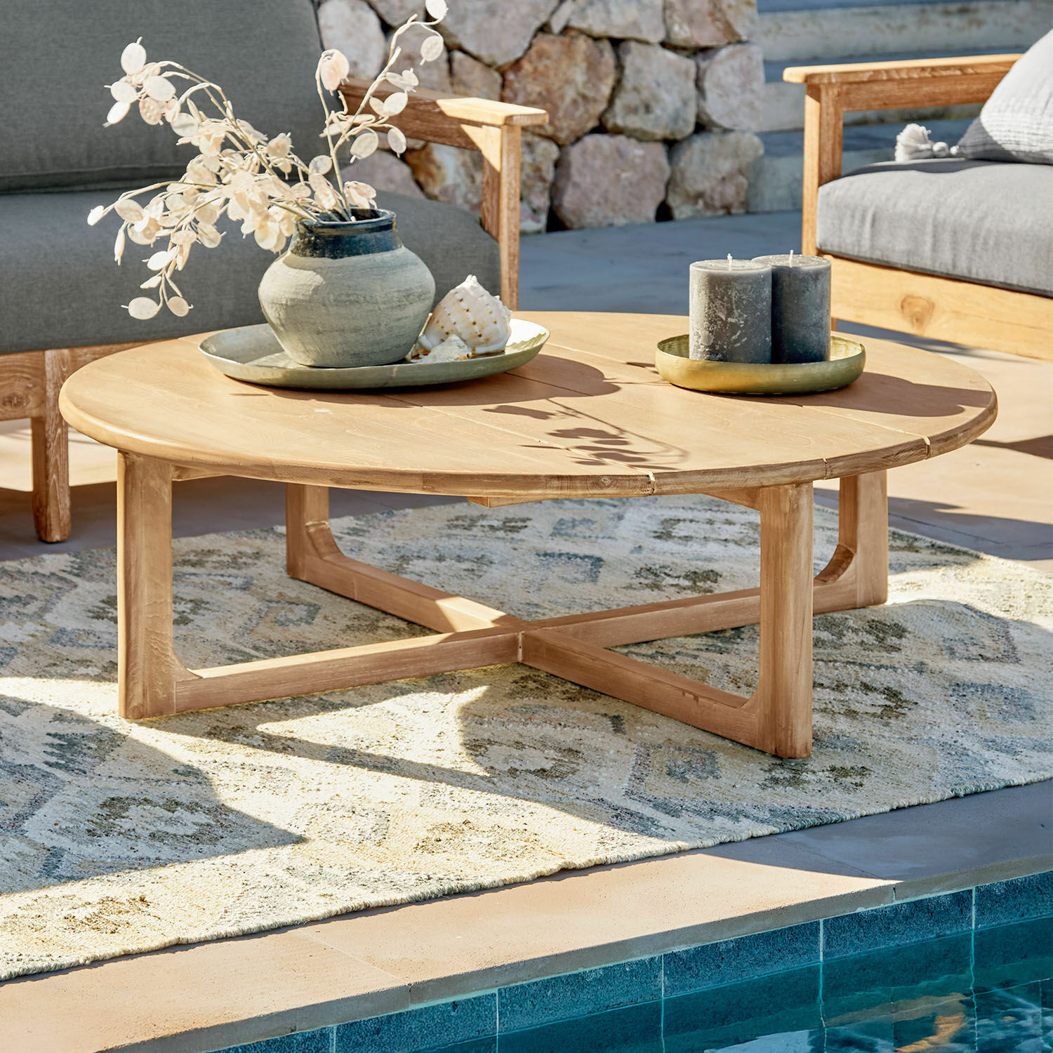 Table basse Tewksbury Table basse ronde en bois de teck naturel sur terrasse au bord de la piscine avec décorations