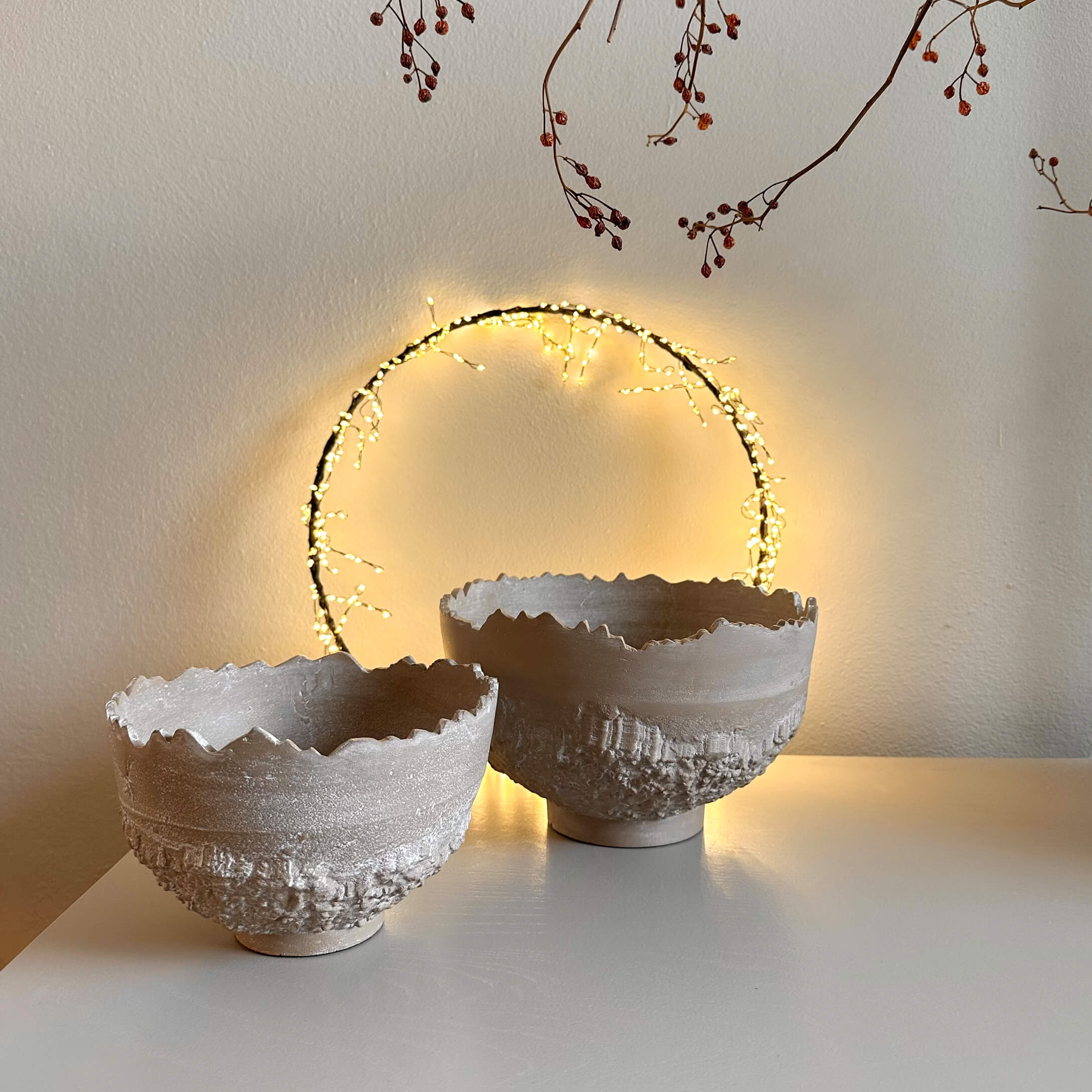 Deux bols décoratifs en céramique beige avec texture rugueuse et bord irrégulier sur table blanche