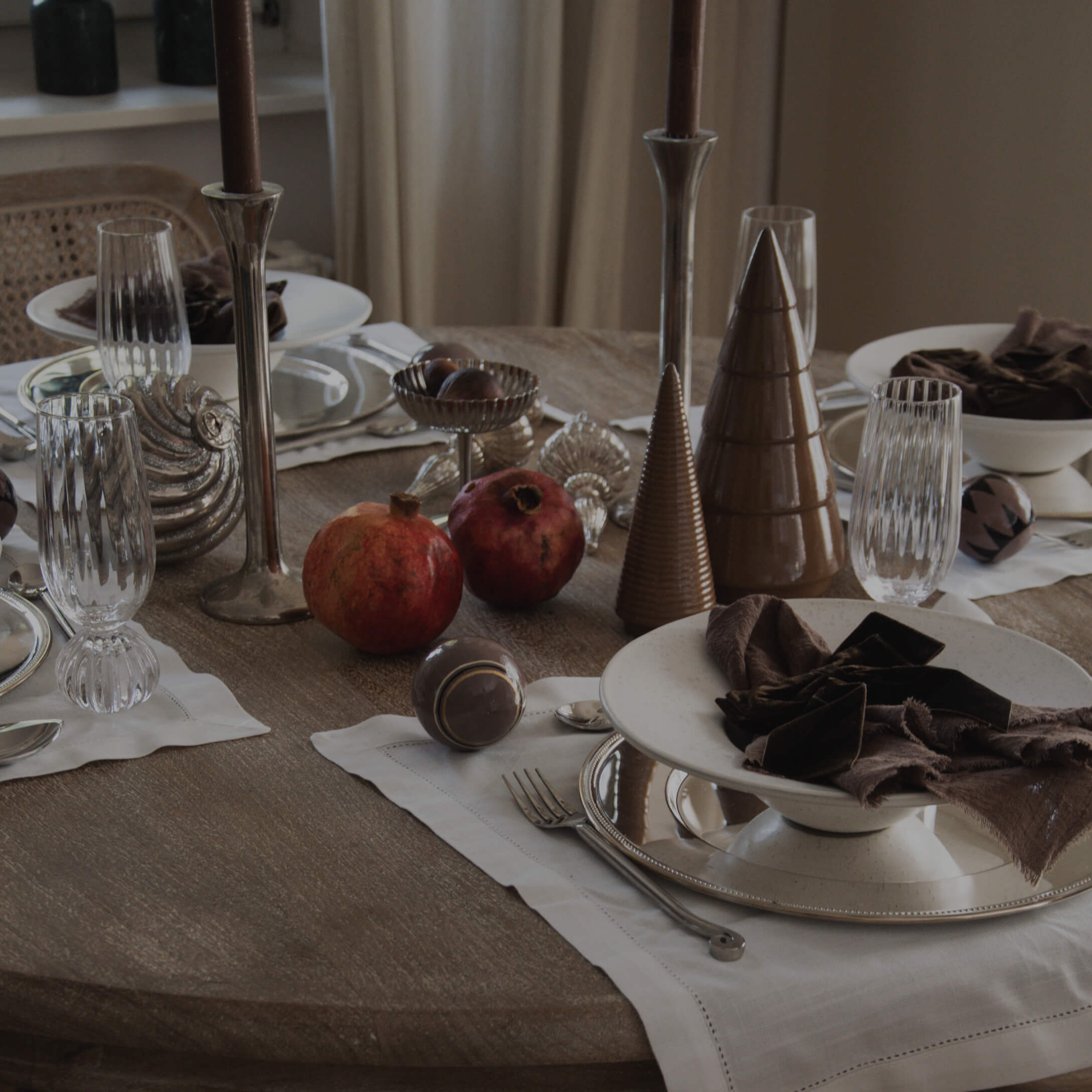 Table élégamment dressée avec cônes en céramique marron, serviettes en tissu et grenades rouges