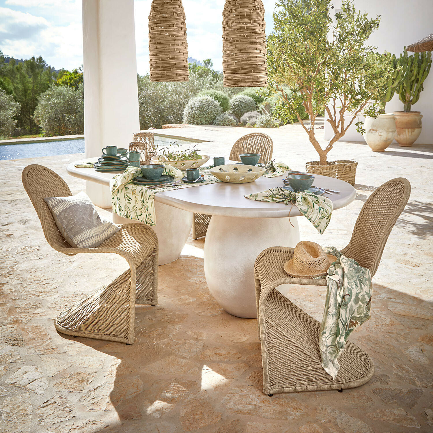 Tafel Arevalon Ovale tafel met wit blad en natuurlijke rotan stoelen op terras met uitzicht op tuin