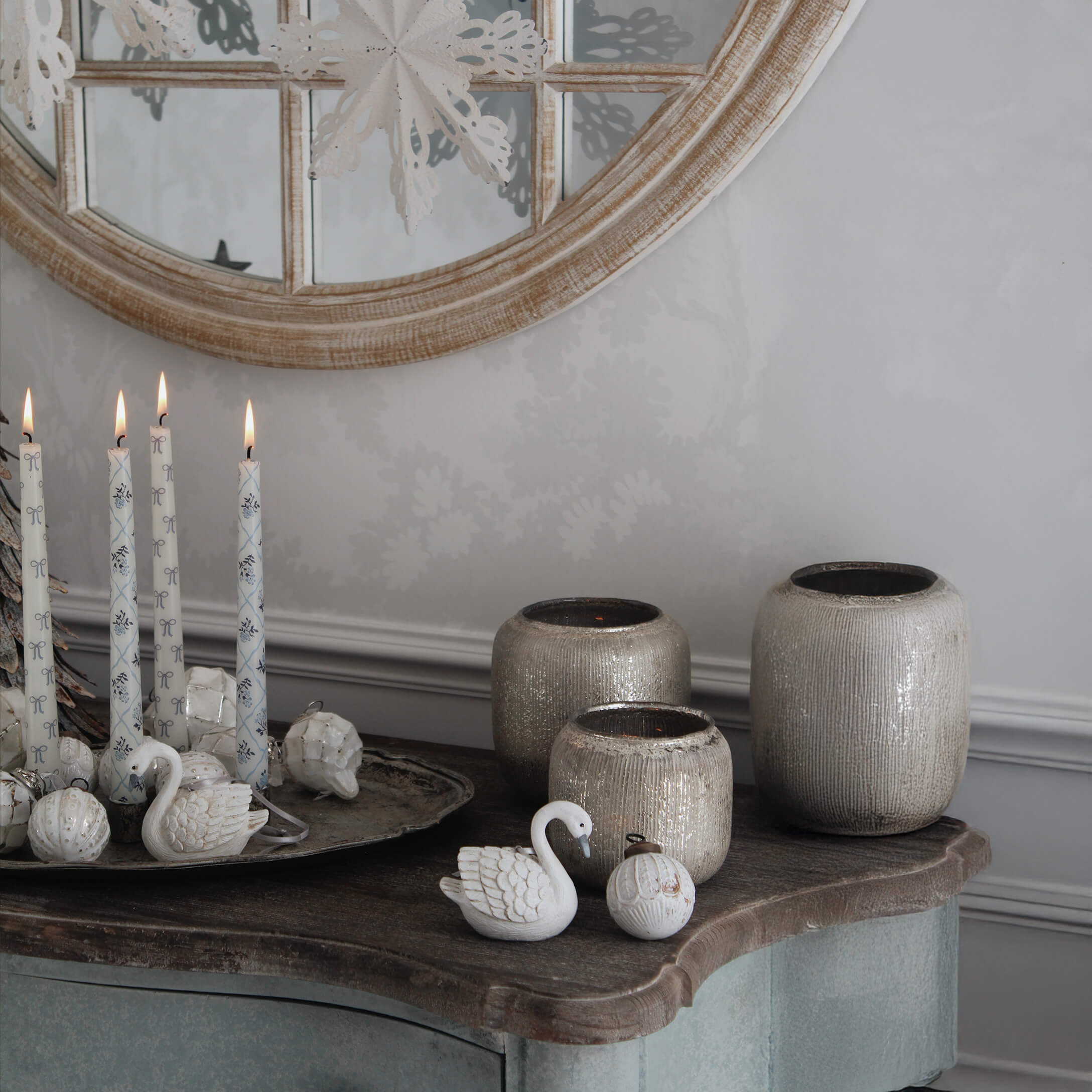 Bougies blanches décoratives et vases en céramique beige sur une table en bois avec miroir en arrière-plan
