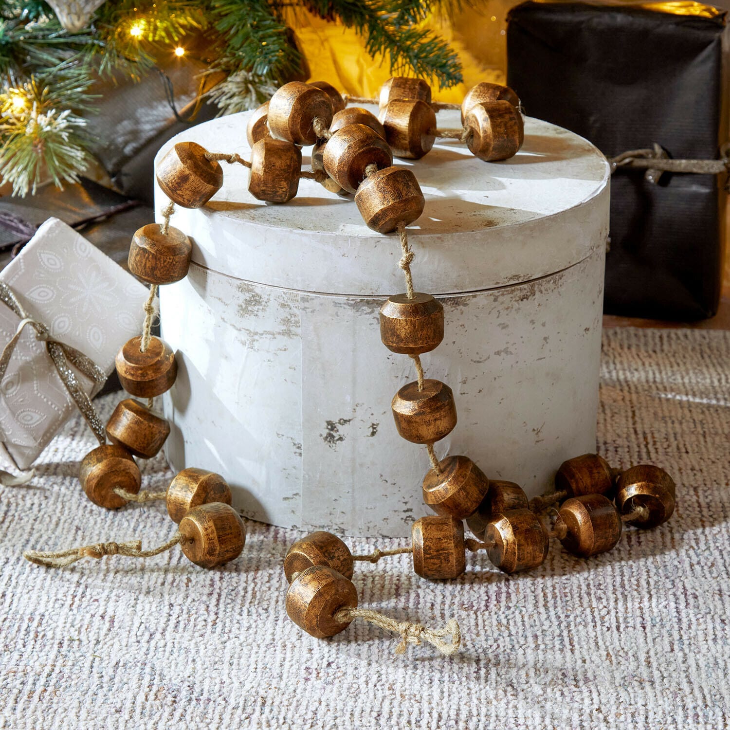 Guirlande Caralinas Guirlande décorative en perles de bois marron posée sur un support clair, décoration festive
