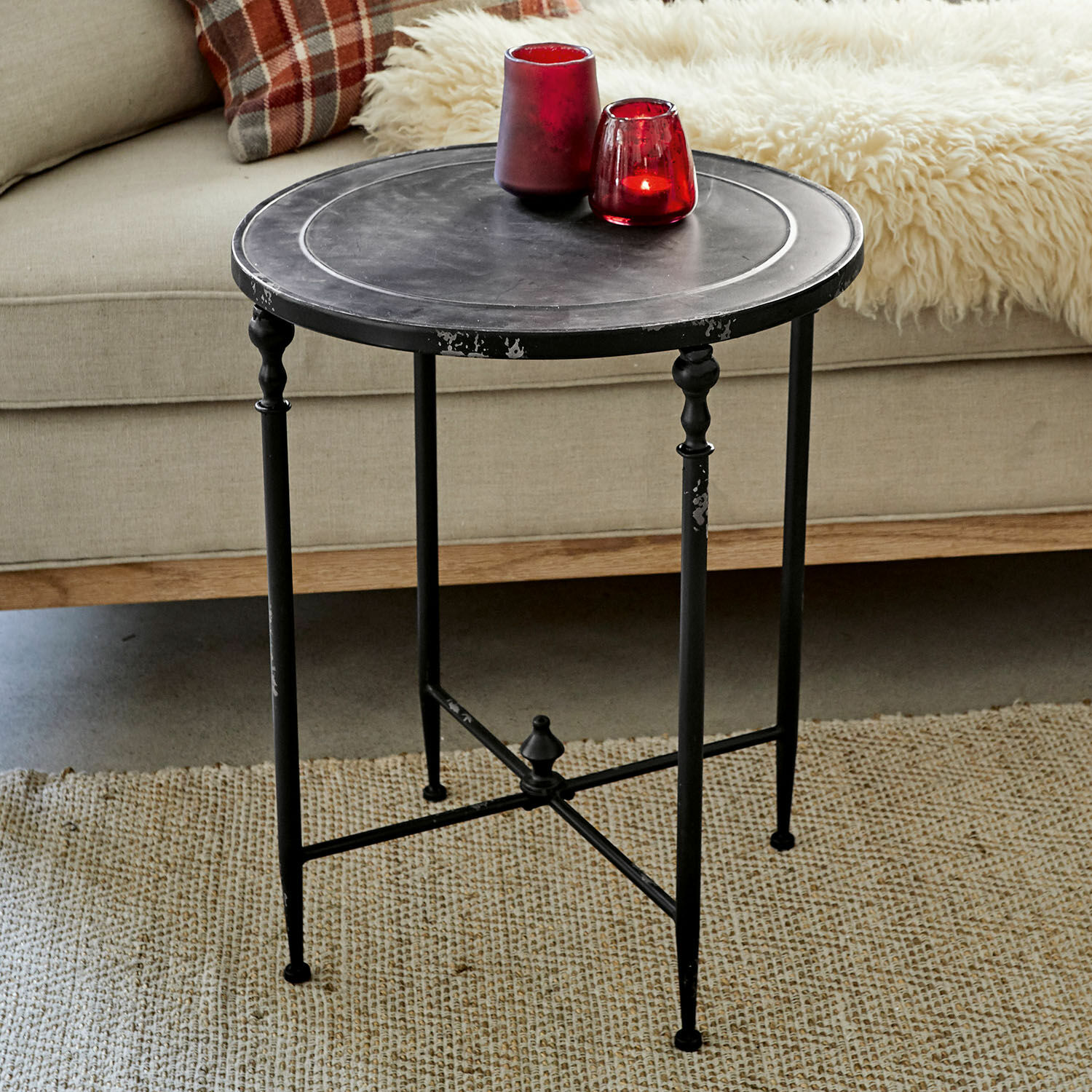 Bijzettafel Danbury Ronde zwarte metalen bijzettafel met decoratieve poten op beige tapijt in woonkamer
