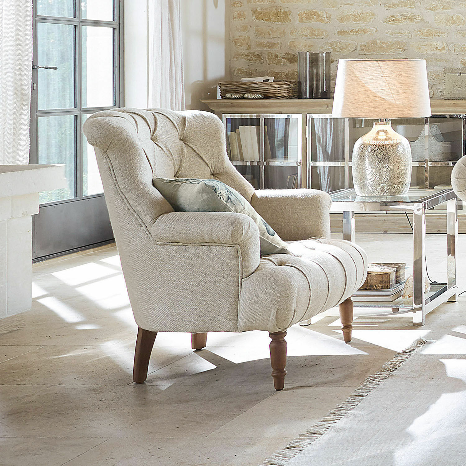 Fauteuil Parranquet Beige gestoffeerde fauteuil met houten poten in lichte woonkamer met lamp en bijzettafel