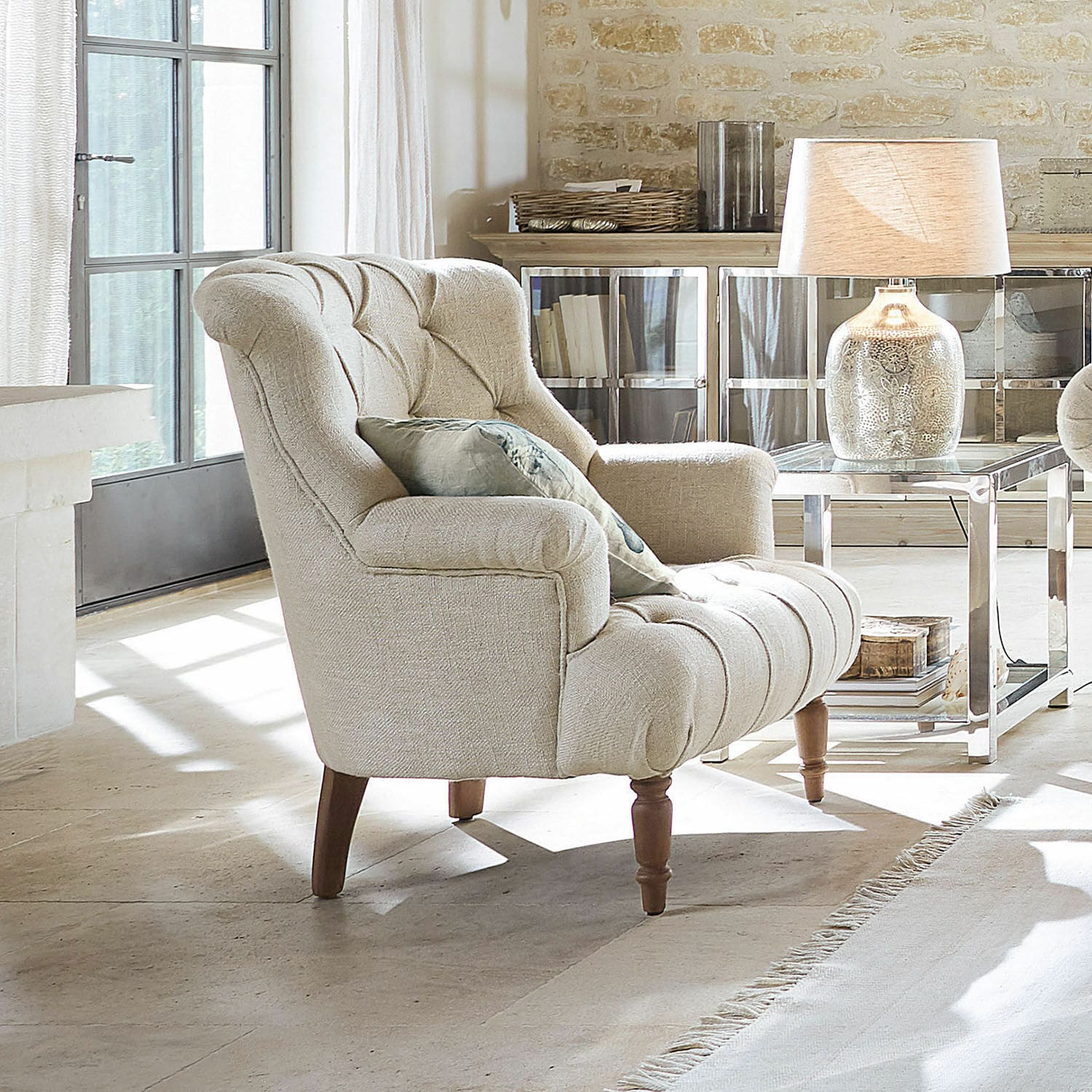 Fauteuil Parranquet Beige gestoffeerde fauteuil met houten poten in lichte woonkamer met lamp en bijzettafel
