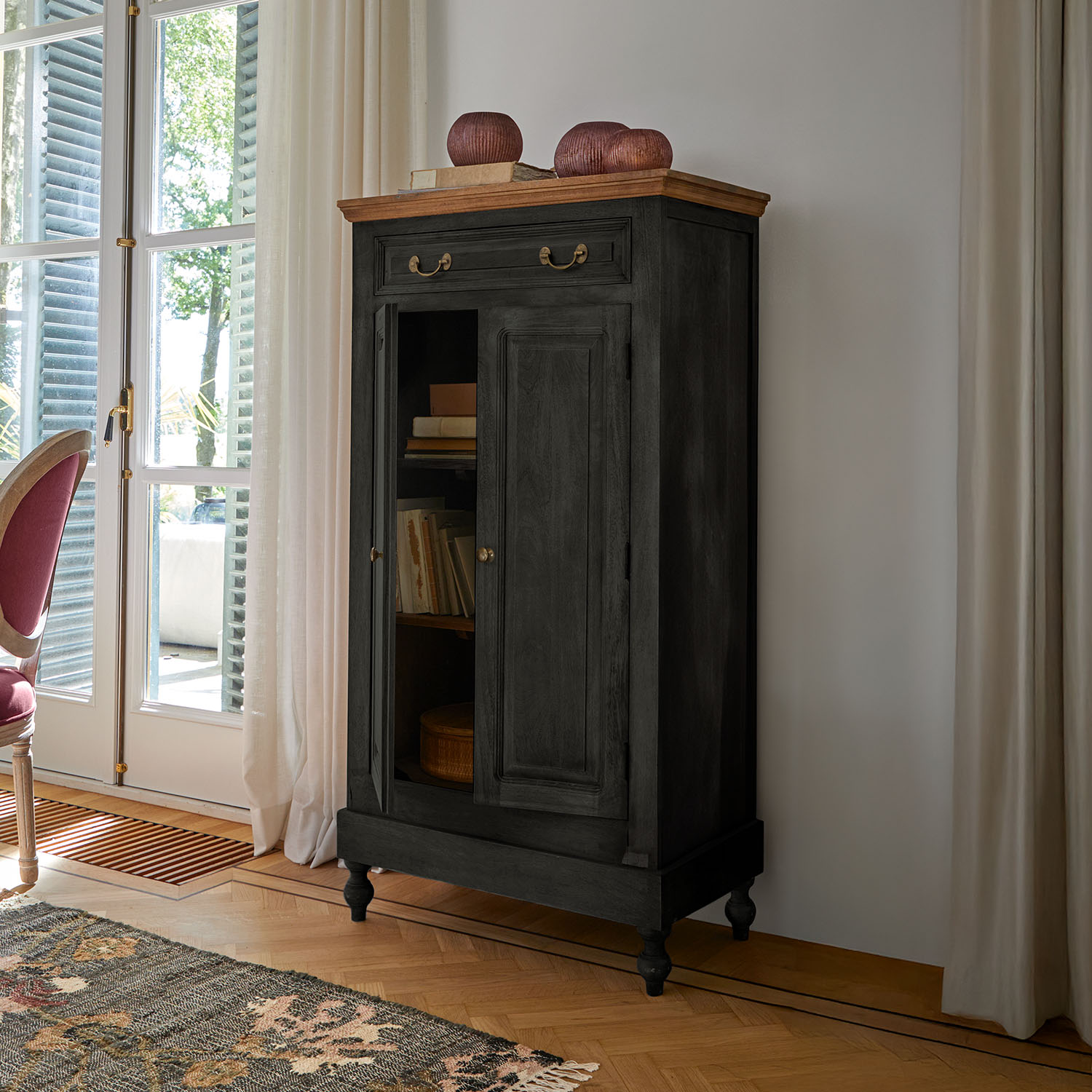 Armoire noire en bois avec plateau clair et poignées en laiton dans un salon classique