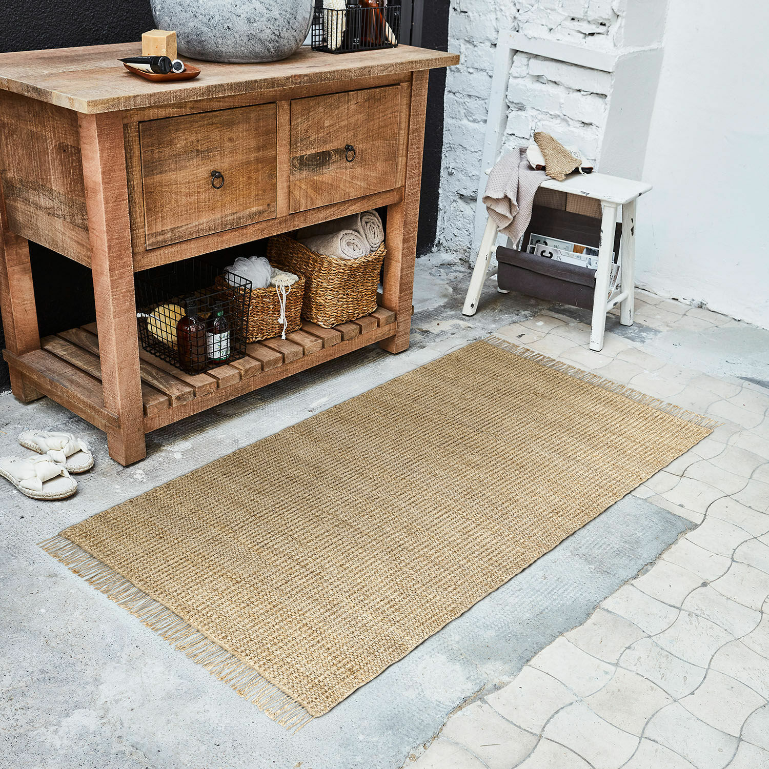 Loper Hermitage Natuurlijke beige jute vloerkleed op de vloer naast een houten kast en een witte kruk