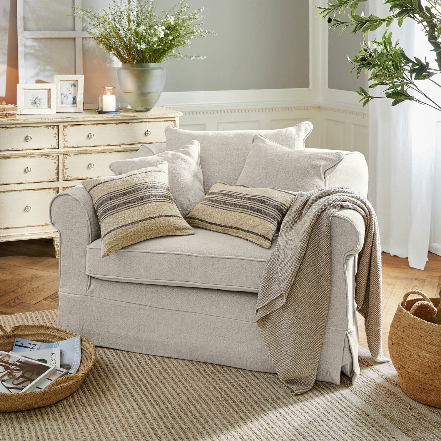 Fauteuil Folsom Beige stoffen bank met gestreepte kussens en deken in gezellige woonkamer met natuurlijke vloerkleed